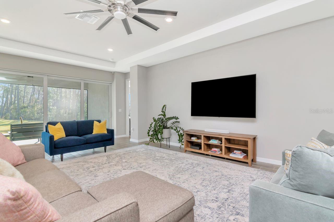 Spacious Livingroom with tray ceiling, upgraded ceiling fan and fantastic views through the panoramic sliding glass doors.