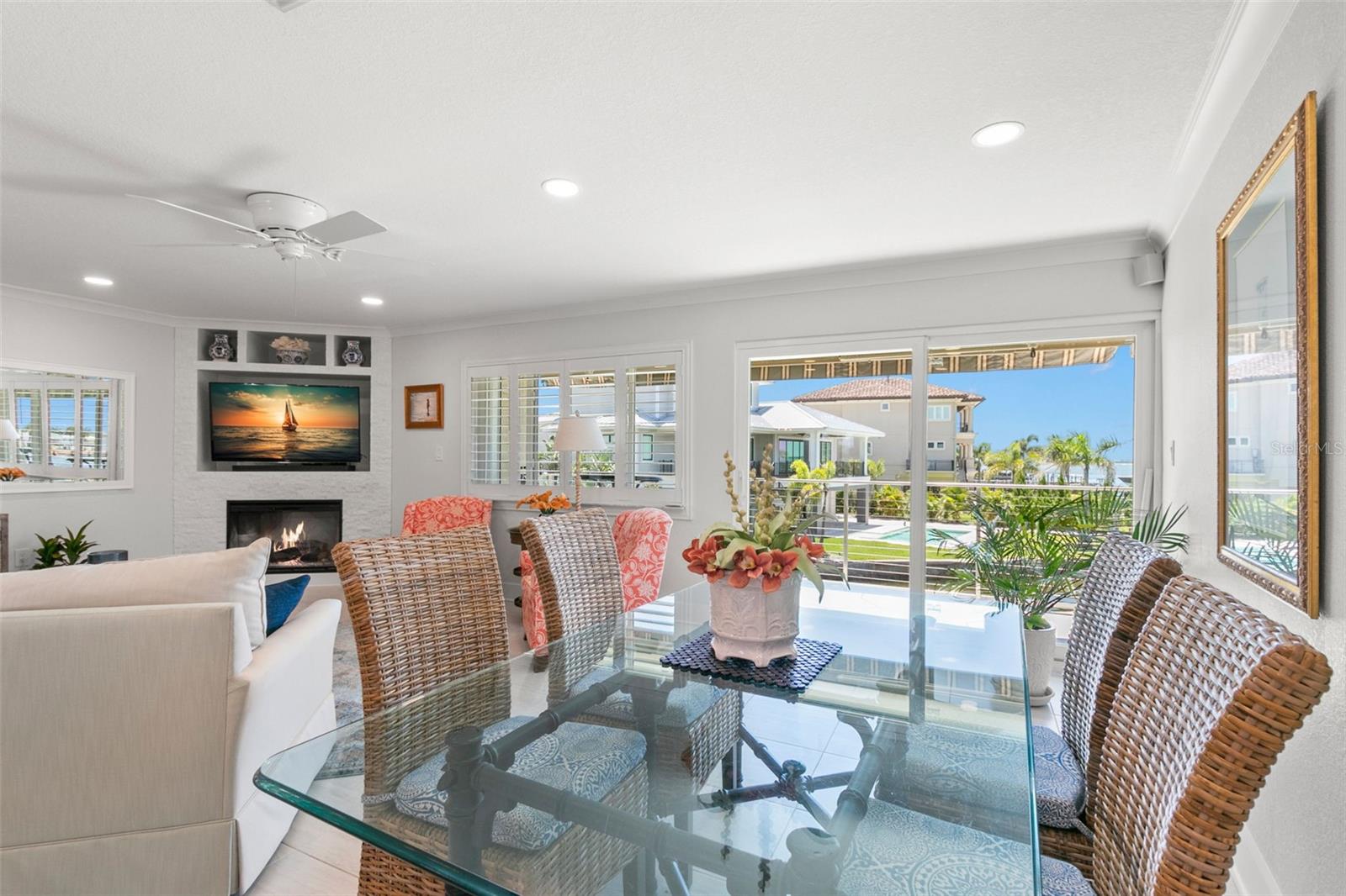Bright dining area with neutral tile flooring and large sliding doors that open to the deck, offering natural light and open water views beyond.