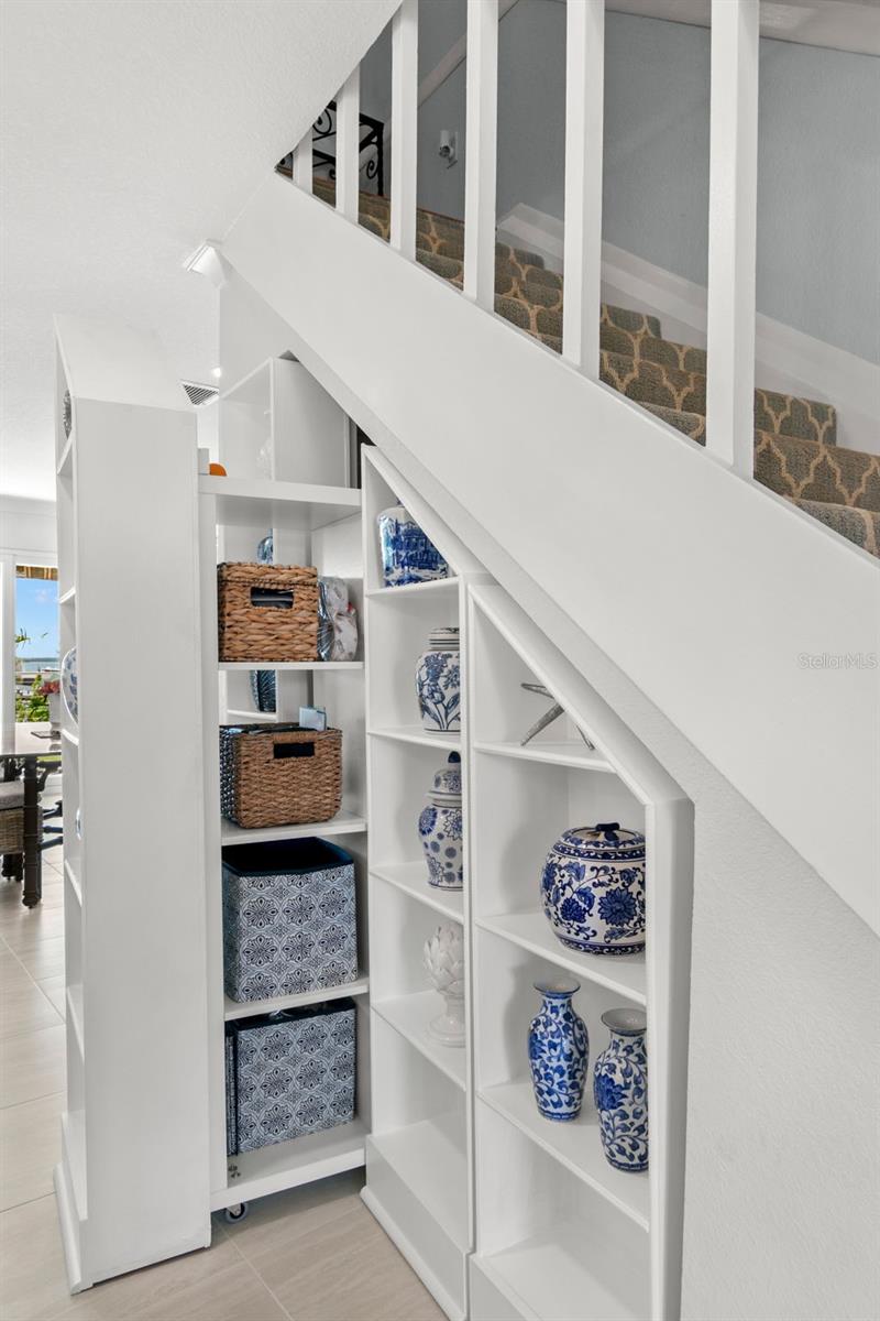Custom built-in shelving tucked beneath the staircase, offering clean, functional storage with a crisp, finished look that maximizes otherwise unused space.