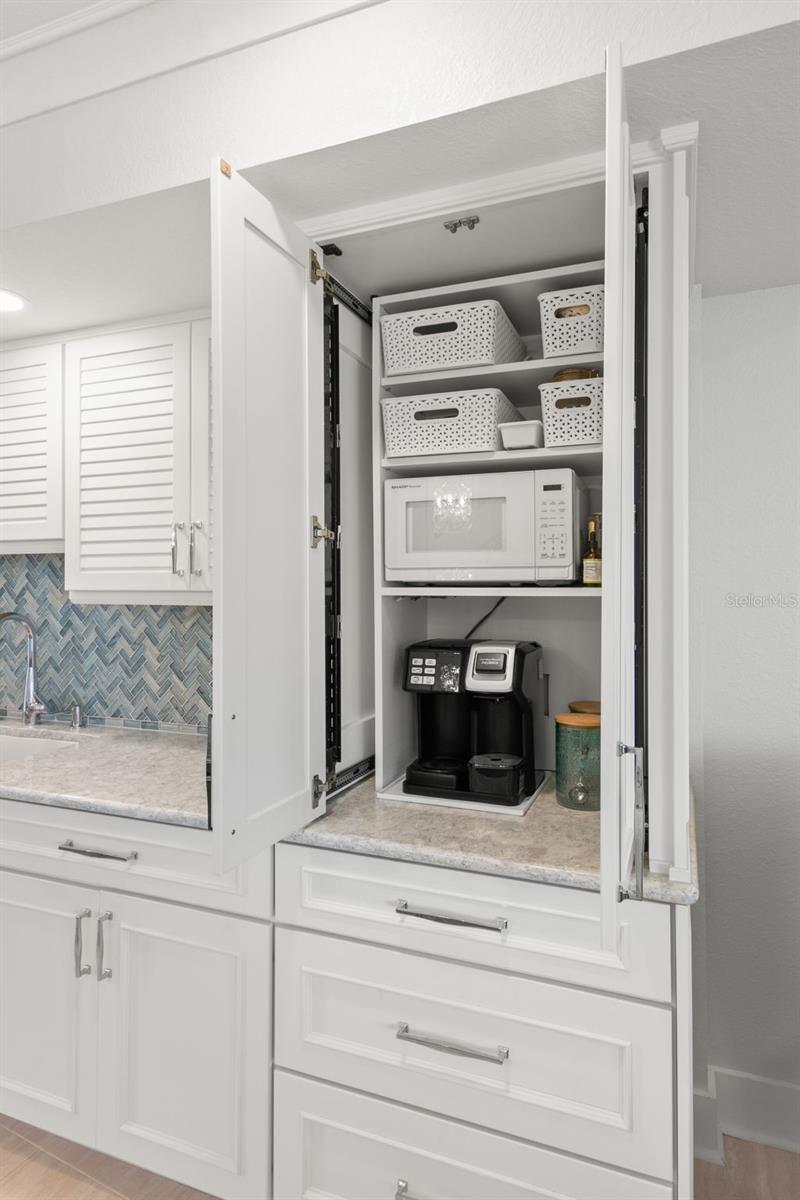 Tall kitchen cabinet with concealed countertop space, interior shelving, and pull-out access—ideal for small appliances and organized storage.