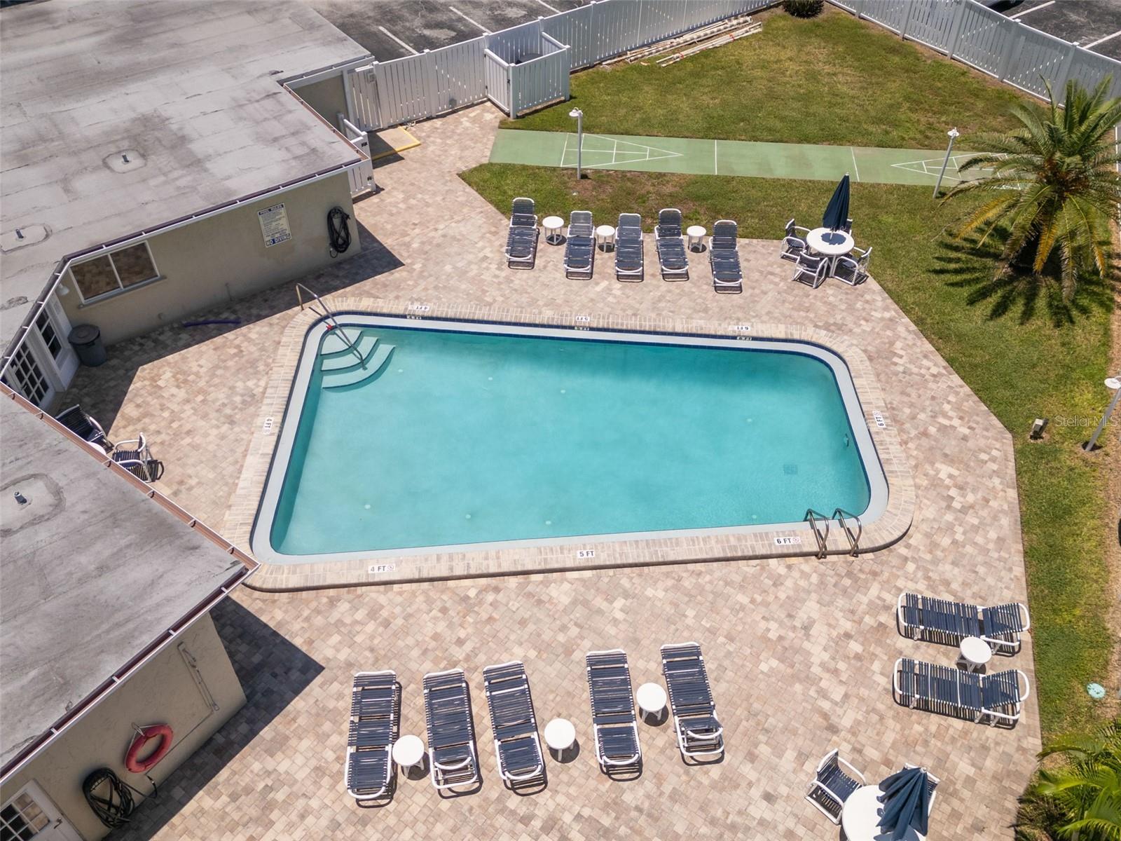 Additional aerial view of the community heated pool and shuffle board area.
