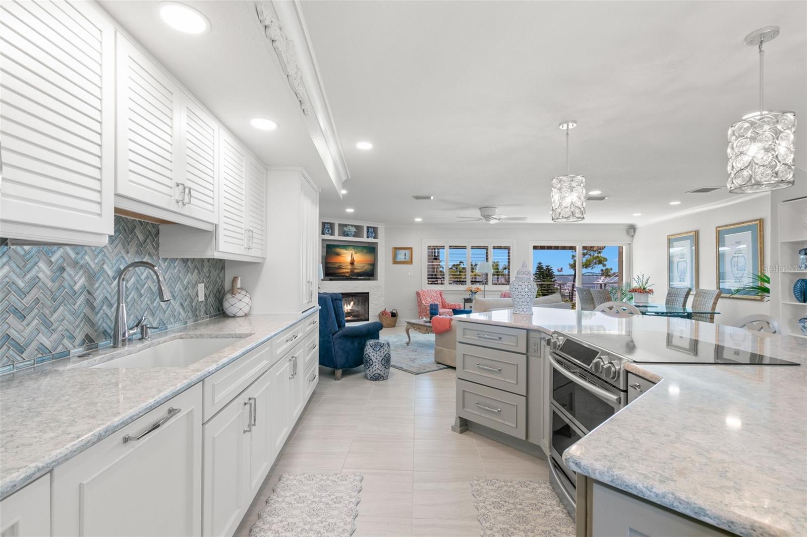 Bright kitchen workspace featuring extensive counter space, stainless steel appliances, custom cabinetry, and a patterned tile backsplash.