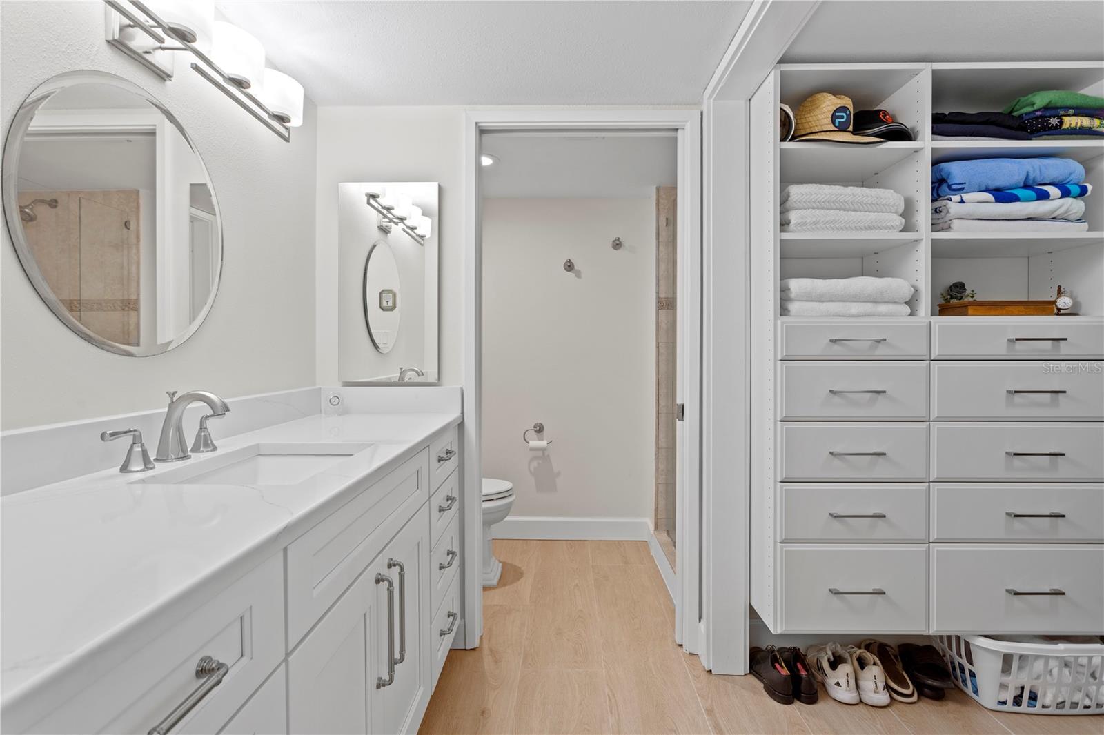 A beautifully updated bath boasting an oversized vanity, walk-in shower, and a custom-organized closet maximizes storage and functionality.