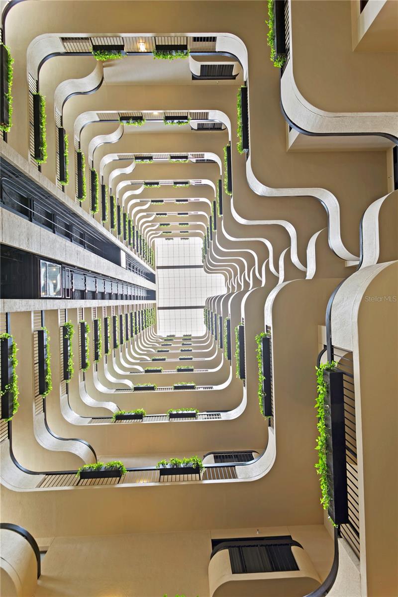 An upward view reveals layered levels, and live greenery bathed in natural light.