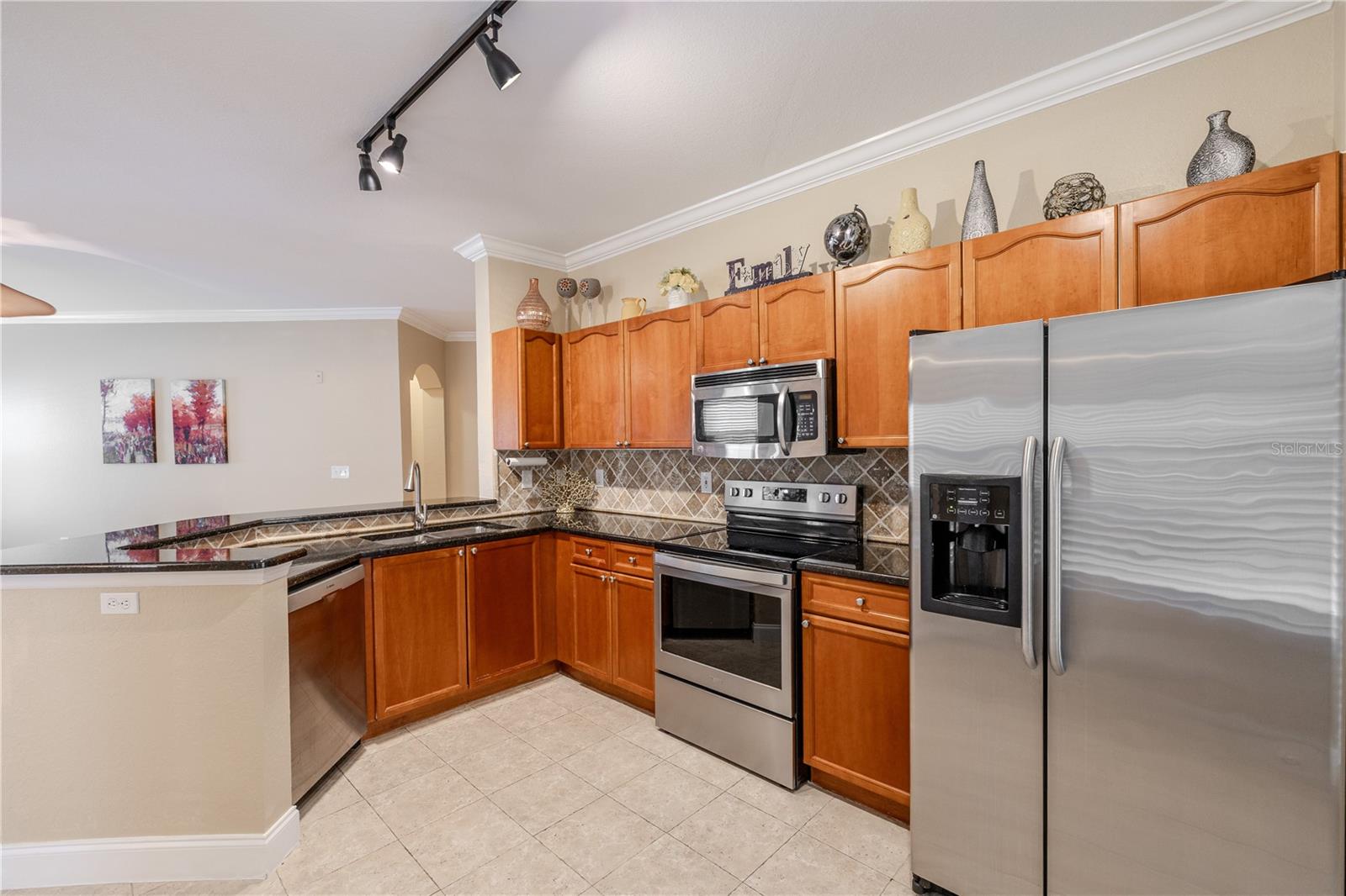 An efficient corner layout maximizes counter and cabinet space while maintaining open sightlines to the living area. Granite countertops, stainless steel appliances, and track lighting combine for a functional, well-organized kitchen designed for everyday use.