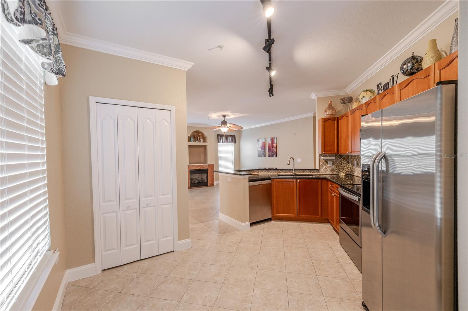 From the breakfast nook, the kitchen’s open layout showcases generous counter space, stainless steel appliances, and a seamless connection to the living area beyond. Track lighting and crown molding add polish, while the pantry closet provides convenient storage close at hand.
