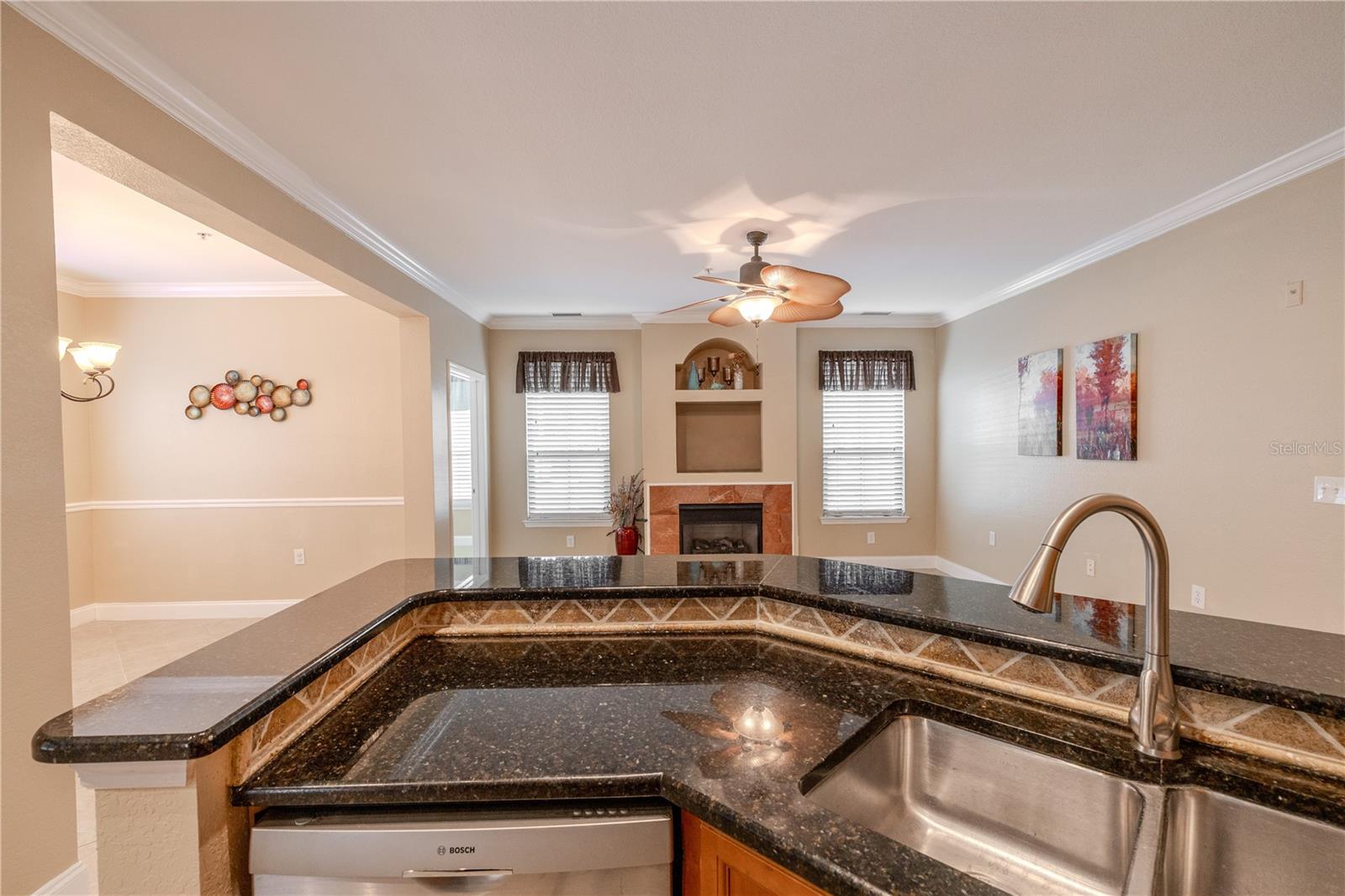 The kitchen overlooks the main living space, creating easy sightlines for entertaining and everyday living. A raised granite counter defines the workspace while maintaining an open, connected feel to the living and dining areas beyond.