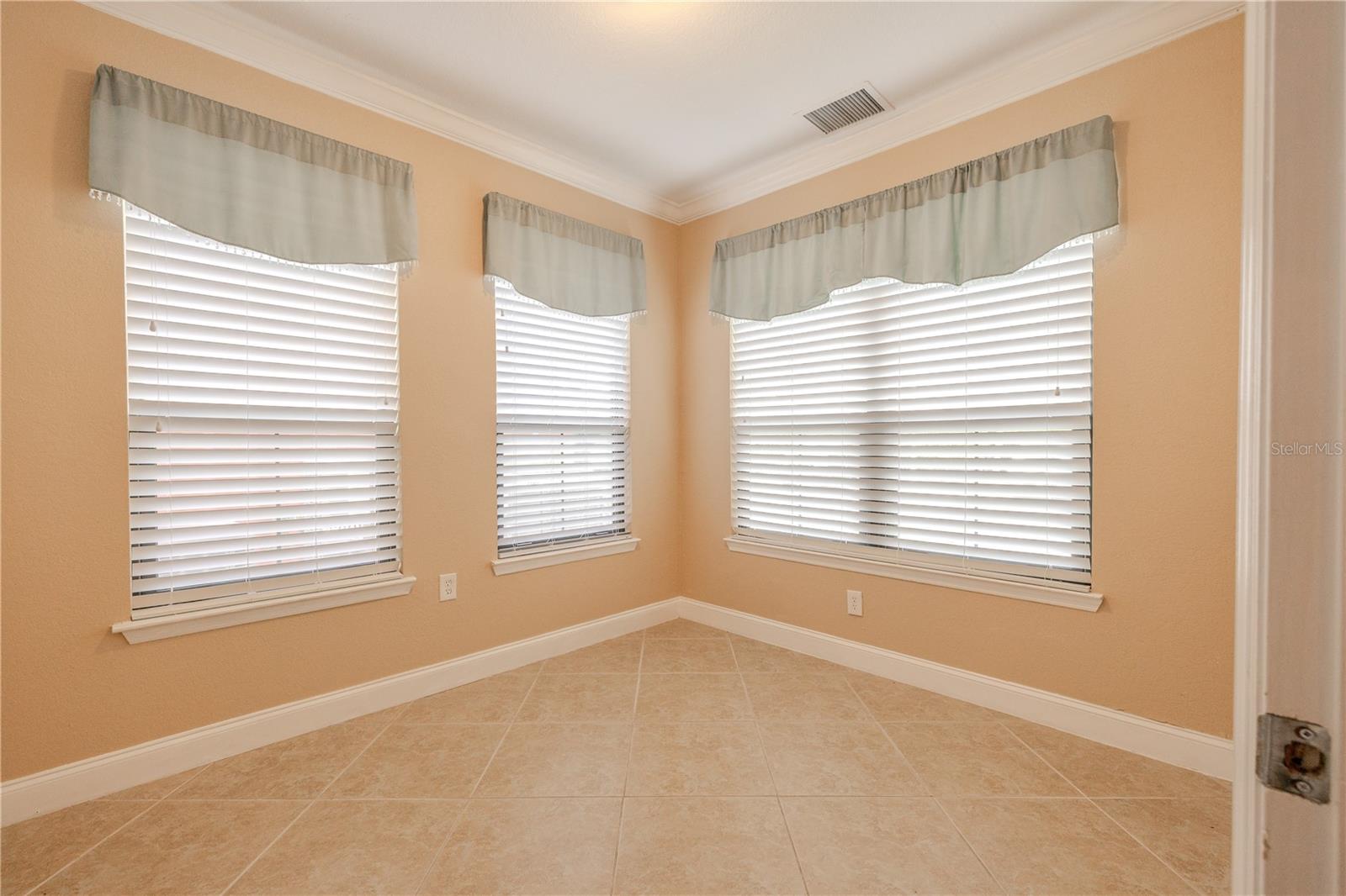 This versatile bonus room features tile flooring, crown molding, and multiple windows that bring in soft natural light. A corner layout enhances flexibility, making the space well suited for a home office, reading room, or creative studio.