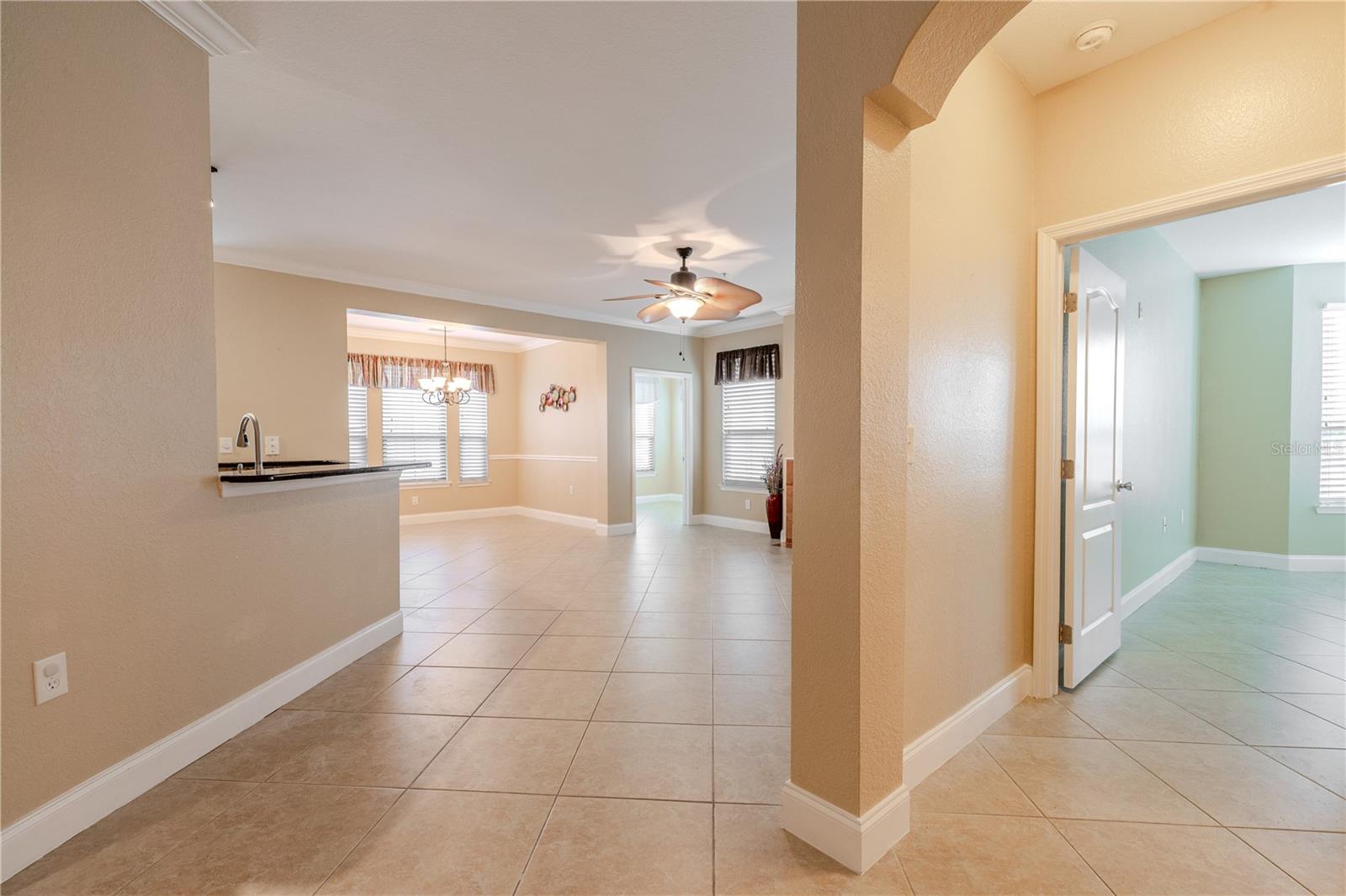 A welcoming foyer opens into a bright, open living space with tile flooring throughout and soft, neutral tones that create a warm, cohesive flow. Sightlines extend toward the main living and dining areas, with an arched entry adding subtle architectural interest and an easy sense of arrival.