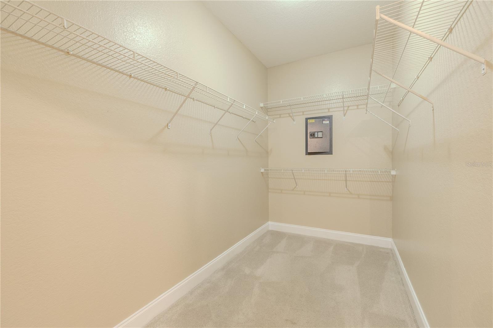 A generously sized walk-in closet offers wire shelving on multiple sides and includes a built-in Bunker Hill wall safe.