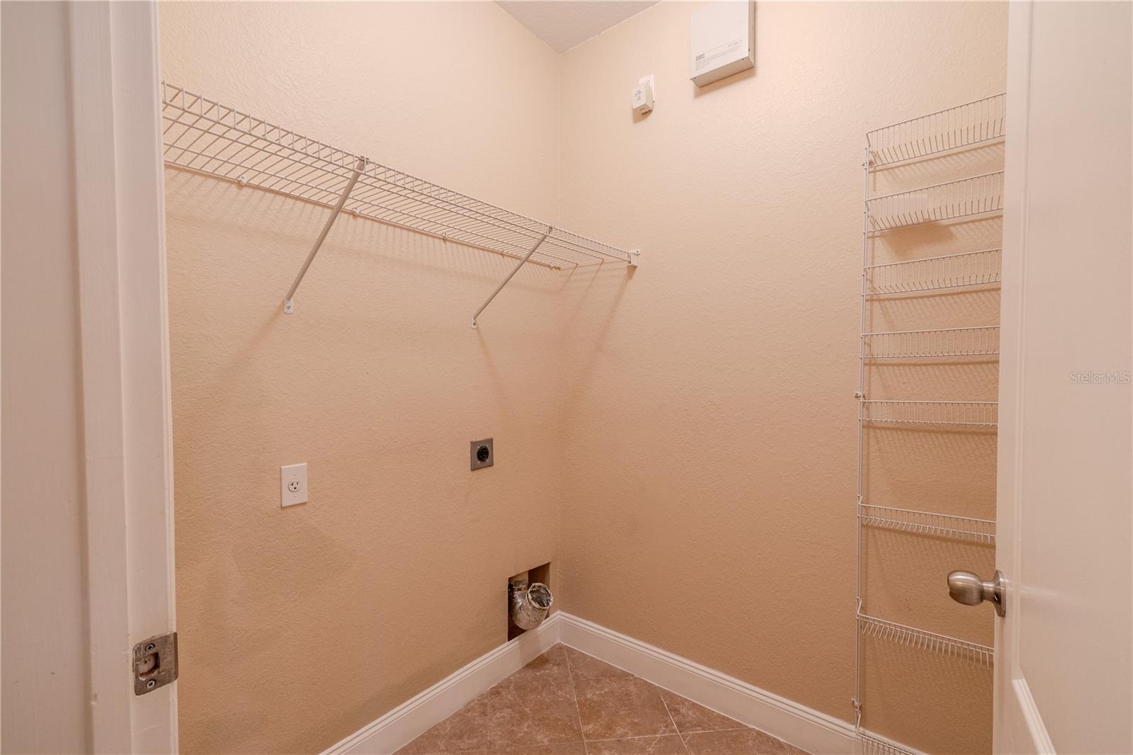 Dedicated laundry room with built-in wire shelving for supplies, vertical storage racks, and washer/dryer hookups, offering a practical, well-organized utility space tucked neatly off the main living areas.