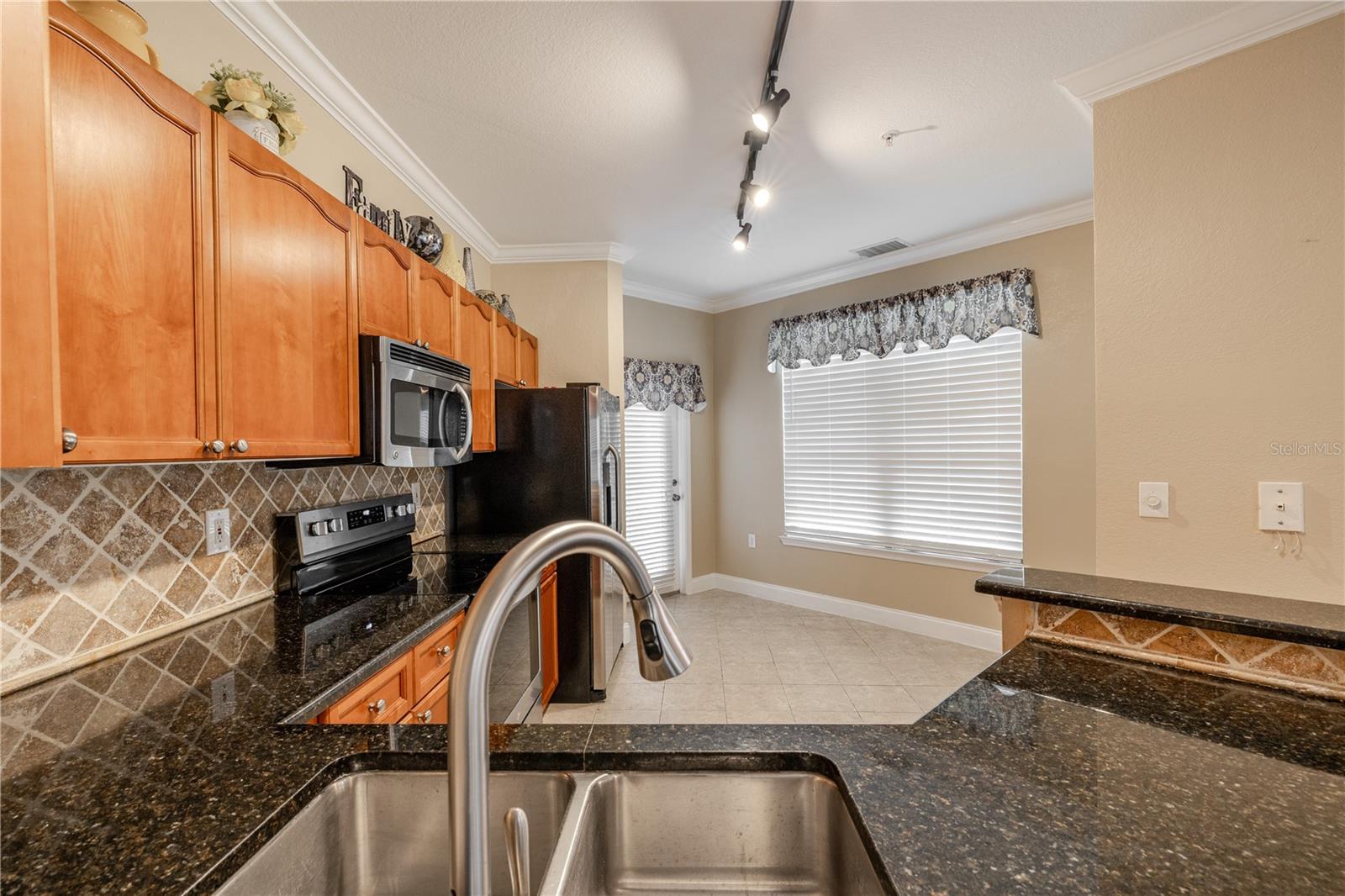 The kitchen opens to a light-filled breakfast nook framed by a large window, offering a comfortable spot for casual meals or morning coffee. Granite countertops, stainless steel appliances, and track lighting continue the home’s cohesive, well-maintained design.