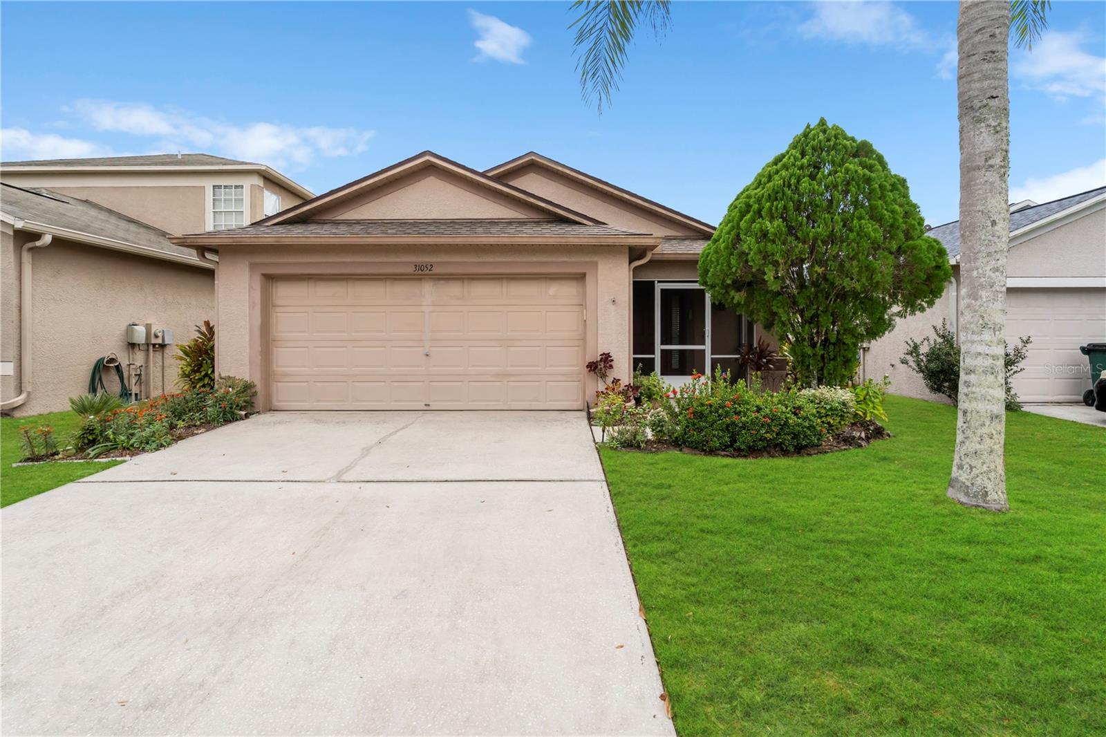 Move-in ready home in Wesley Chapel with inviting curb appeal, manicured landscaping, and a screened front entry in a quiet residential neighborhood.