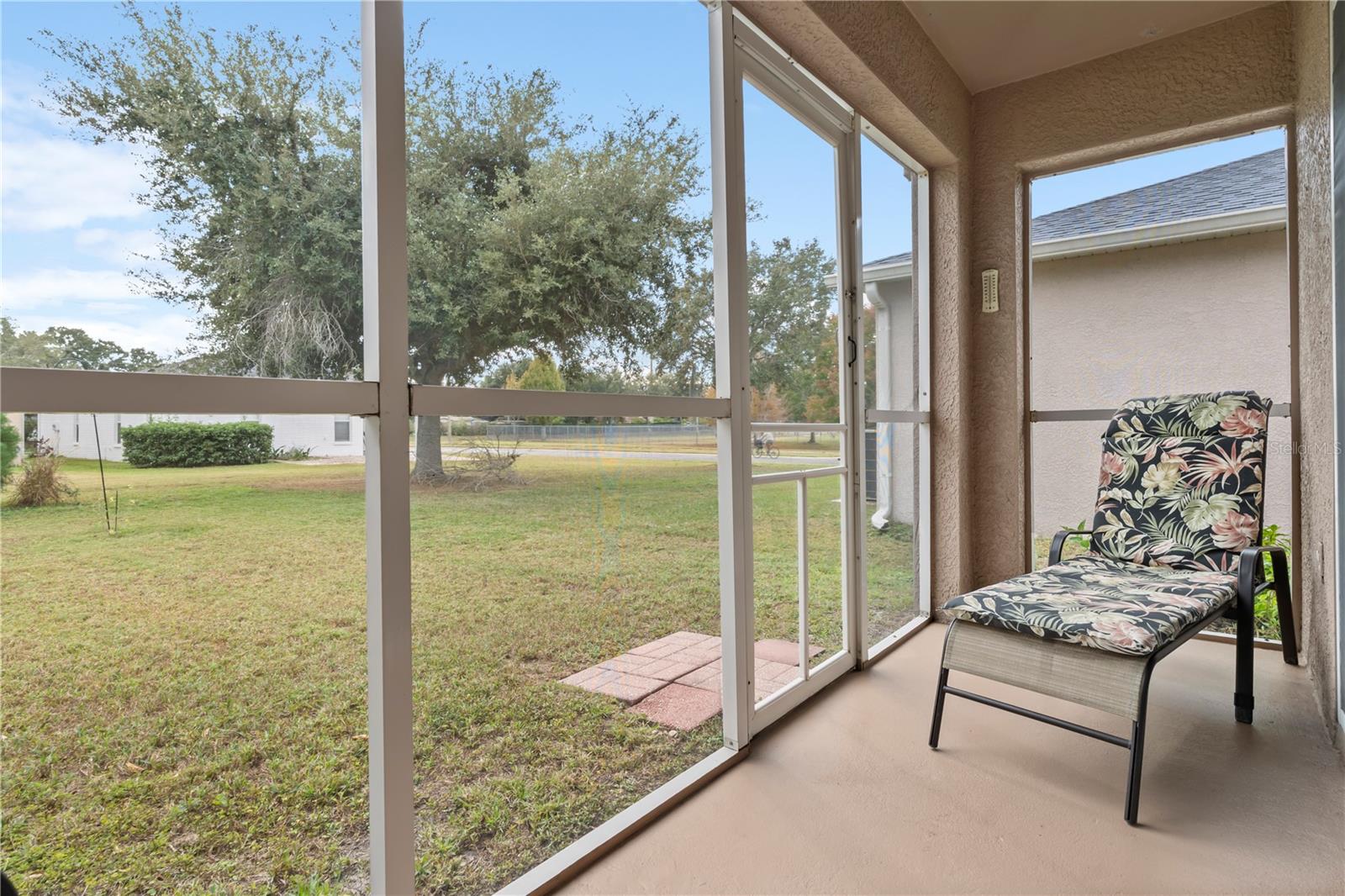 Screened lanai overlooking the spacious backyard, offering a relaxing outdoor retreat for morning coffee or evening downtime.
