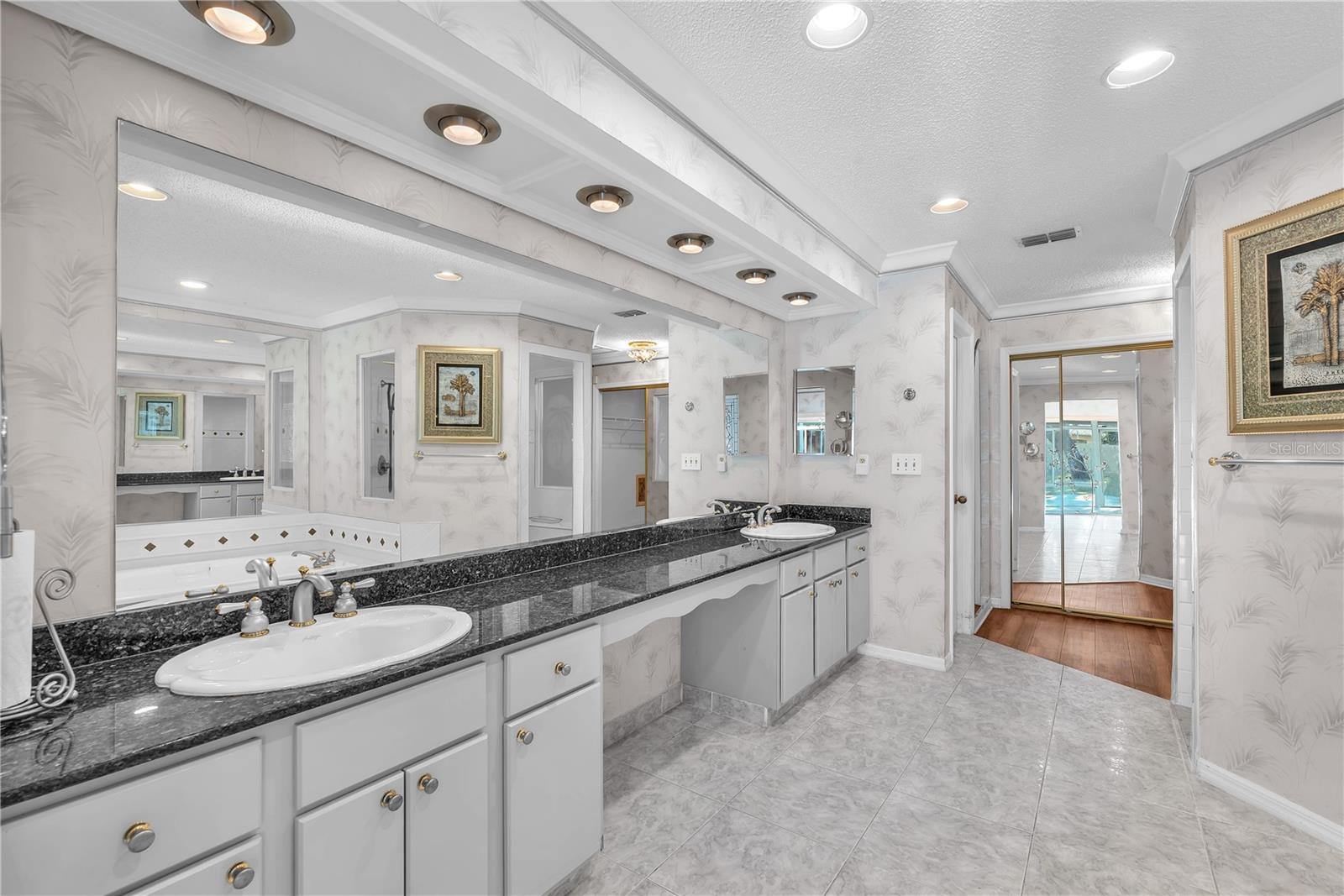 This luxurious ensuite has a shower, garden tub, dual-sink vanity, plus a separate tiled warming/dressing room.