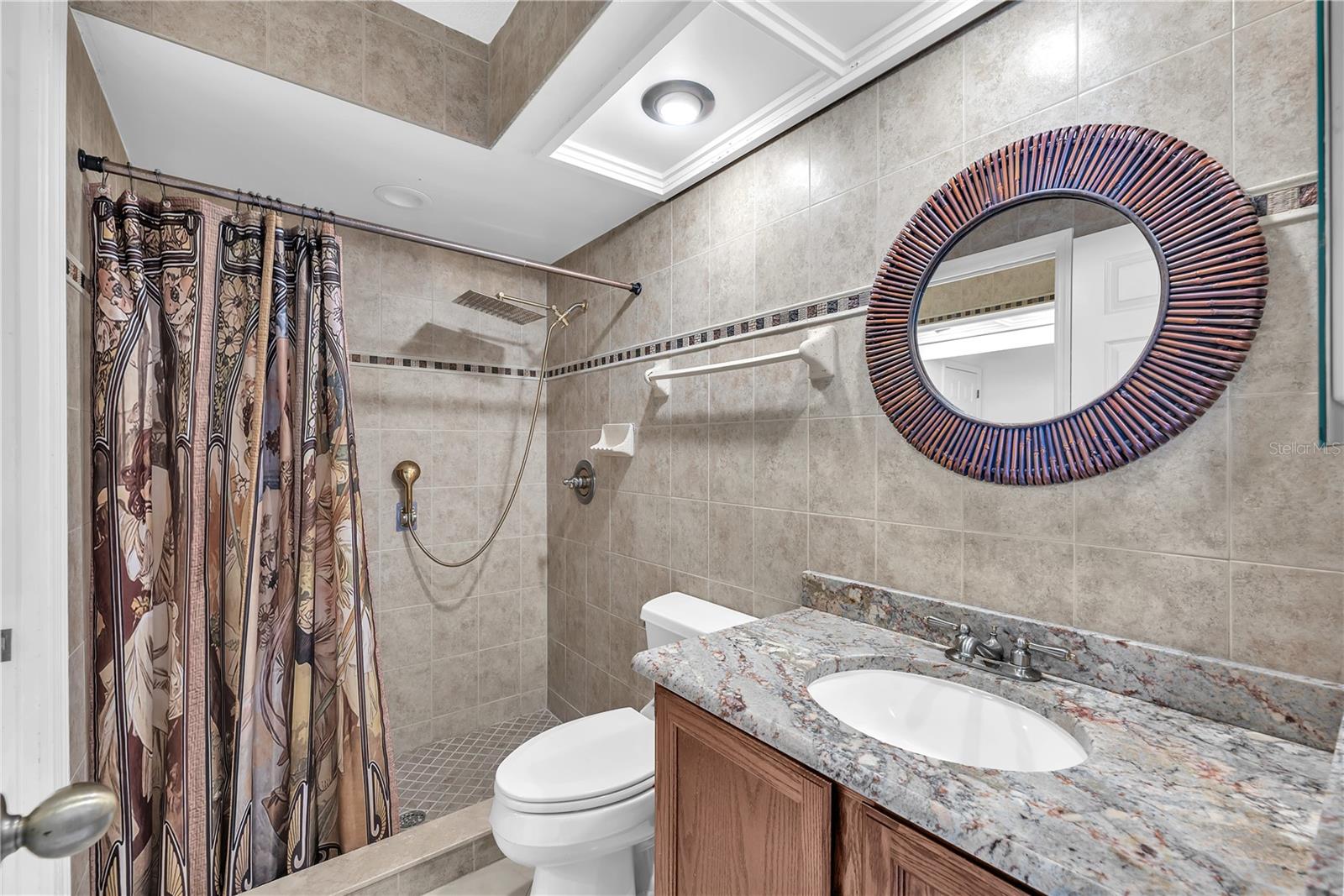This Jack-and-Jill bathroom, featuring a spacious shower, sink with granite counter and toilet connect two of the secondary bedrooms.