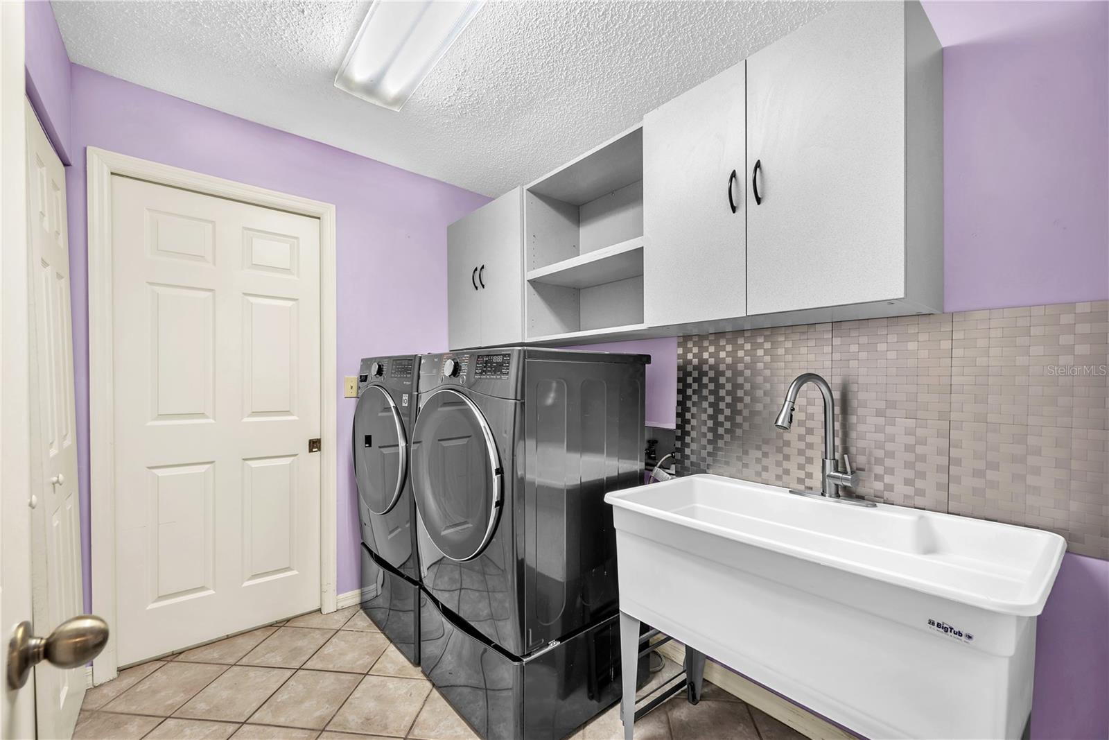 A pass-through utility room offers laundry, a large storage closet, and a double utility sink and connects the guest wing to the kitchen.