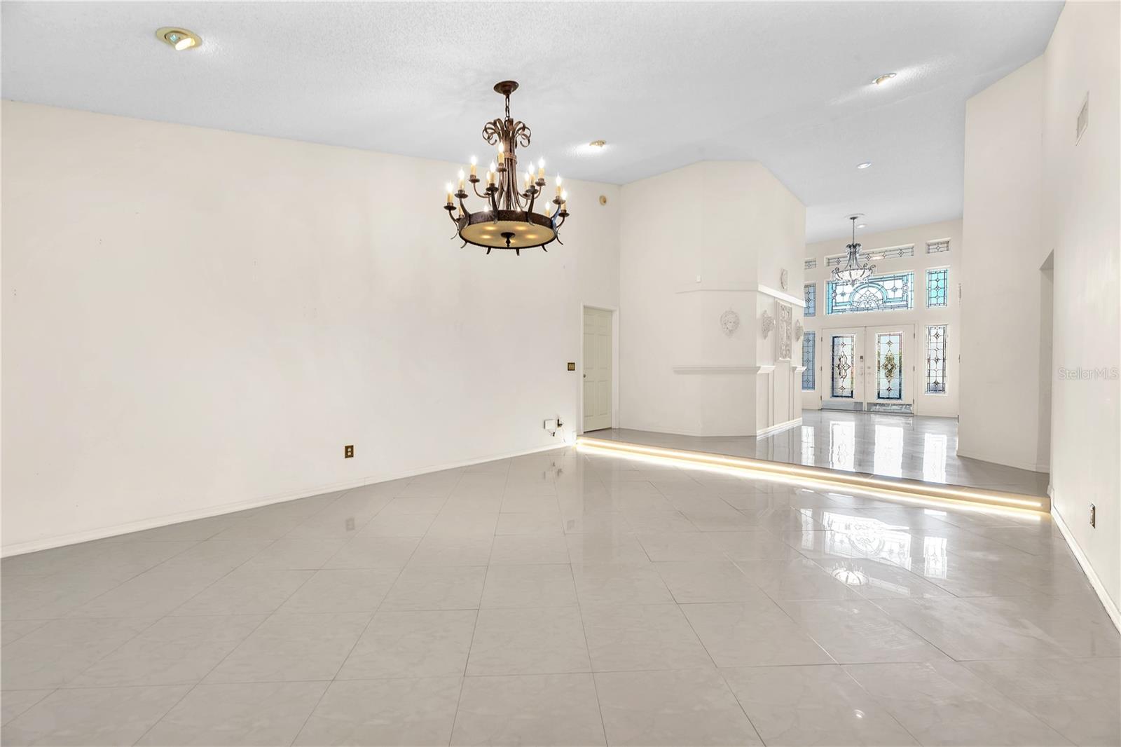 The formal living room looking back into the foyer, showcasing the stunning leaded glass entryway.