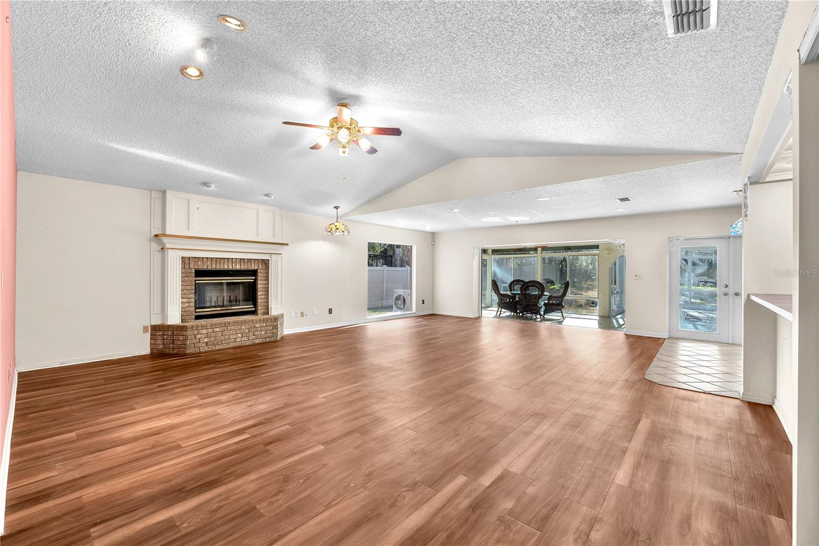 The family room is warm and inviting with a wood-burning fireplace, oversized windows that flood the space with natural light, and a built-in wet bar—ideal for entertaining.