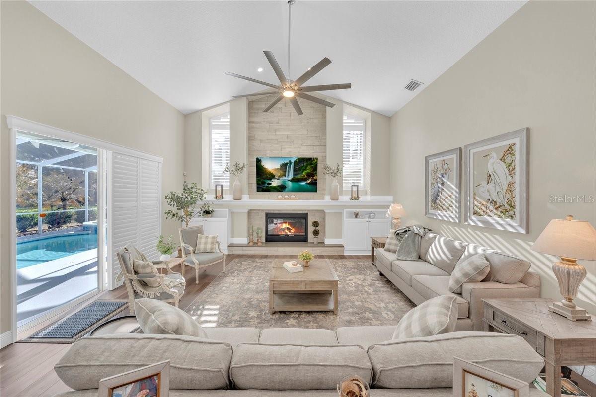 Bright family room featuring vaulted ceilings, statement ceiling fan, and a dramatic fireplace wall with built-ins!