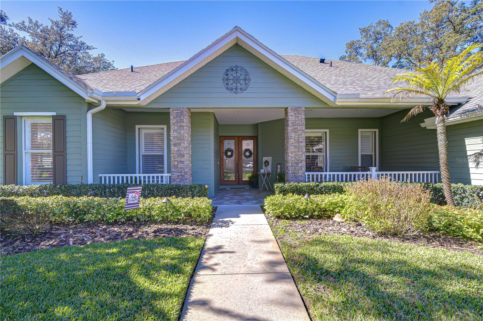 Welcoming front porch with stone columns, double entry doors, and manicured landscaping!