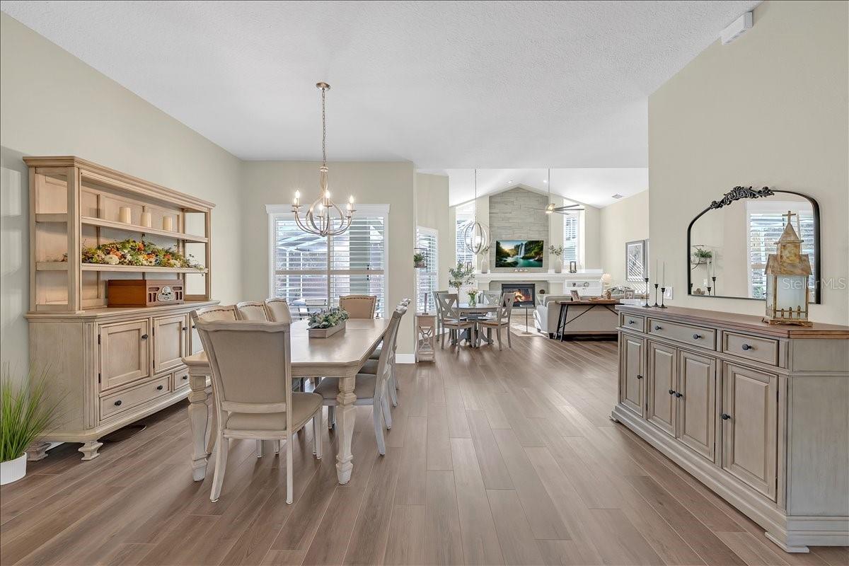 Open-concept dining room flows to family room, featuring wide-plank floors, shutters, and fireplace!