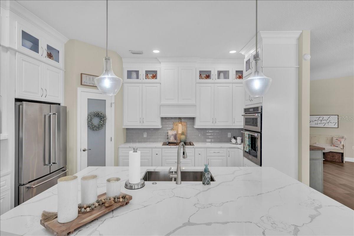 Quartz island, crisp white cabinetry, subway tile backsplash, and double wall ovens!