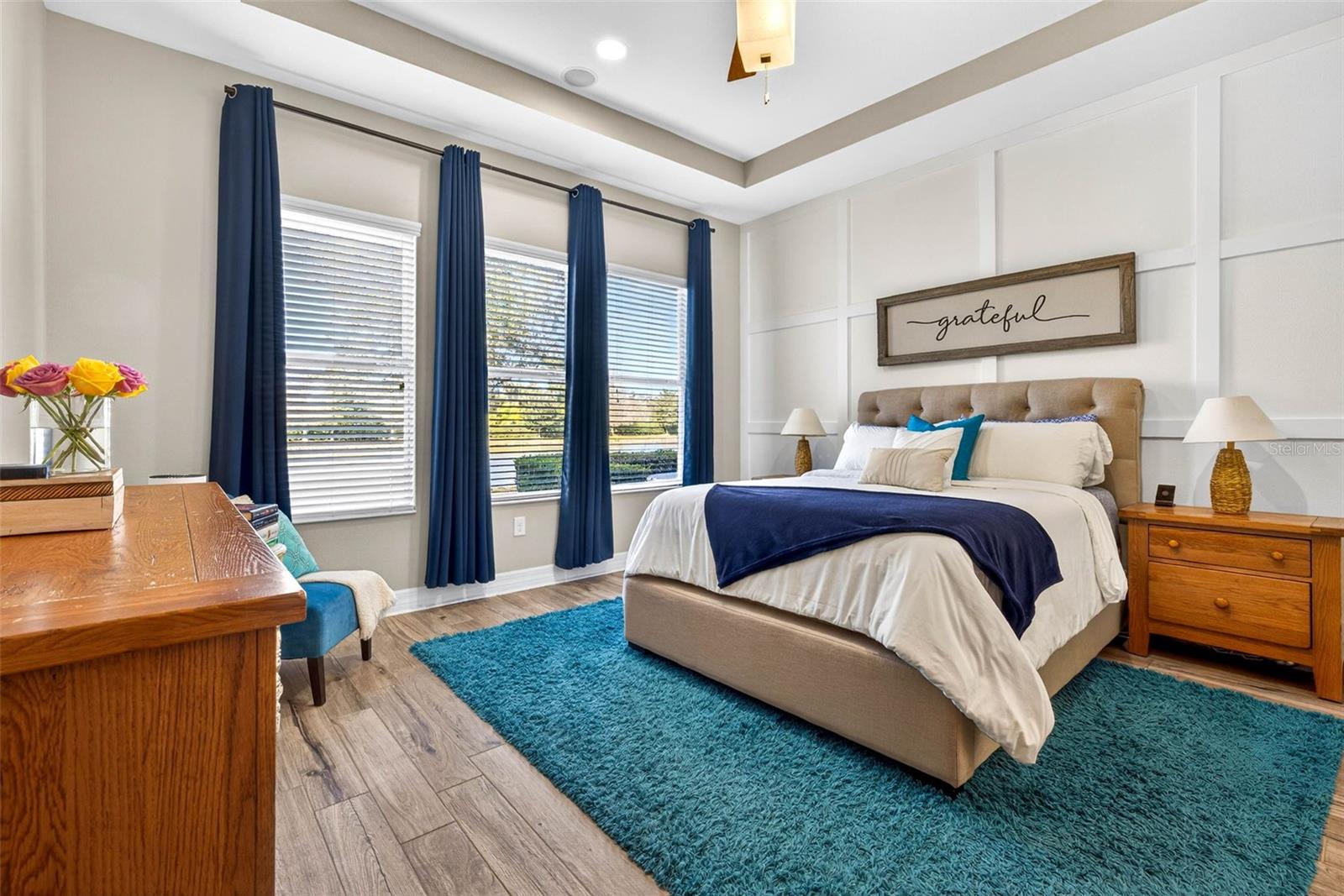 Primary bedroom with accent wall, tray ceiling, gorgeous back yard views.