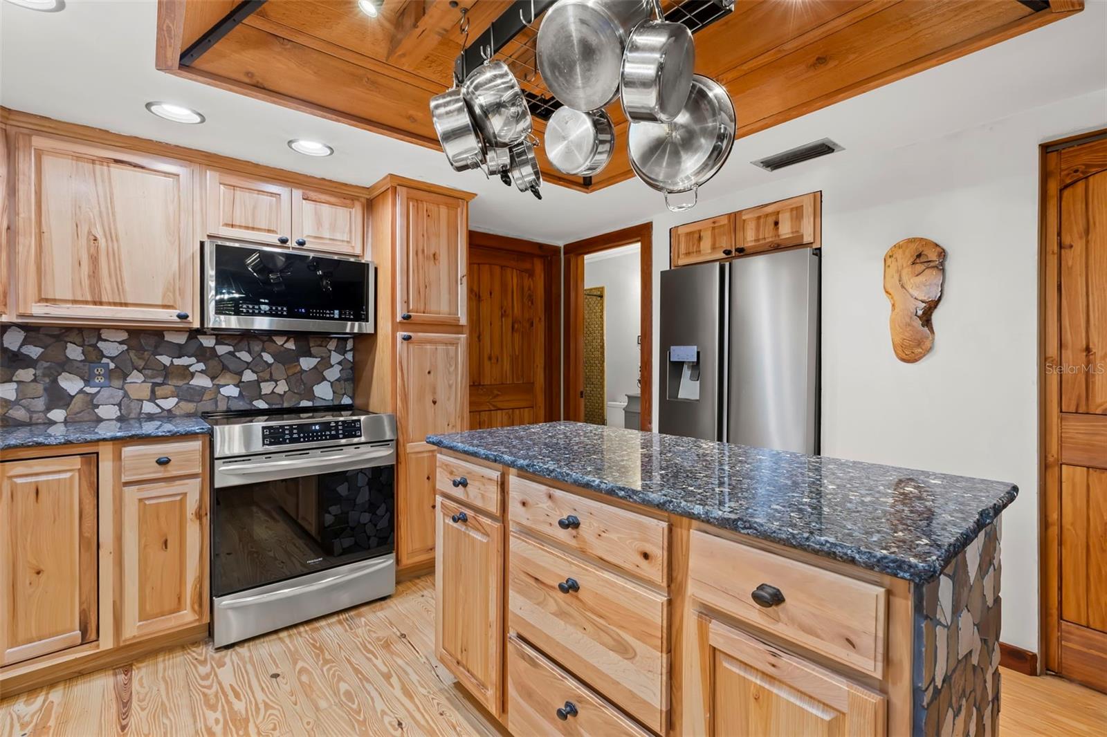Cooking area showcasing updated appliances, wood cabinetry, and a cohesive blend of natural textures that reinforce the home’s handcrafted character.