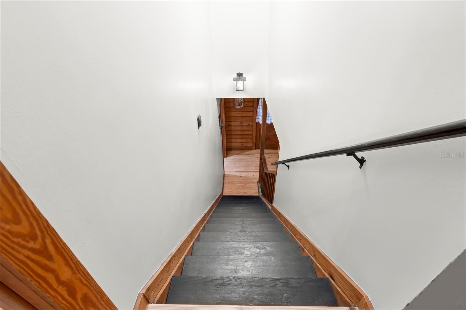 Staircase to the second level featuring solid treads, painted risers, wood trim, and a modern handrail, creating a crisp transition between levels while maintaining the home’s warm wood accents.