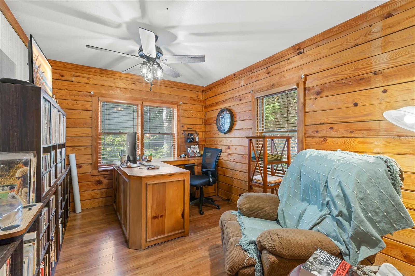 This bedroom embraces a true cabin feel with continuous solid-wood plank walls and exposed log detailing that bring warmth and texture to the space. Natural light filters through wood-trimmed windows, enhancing the organic tones of the woodwork and flooring. The result is a calm, cozy retreat that feels grounded and private.