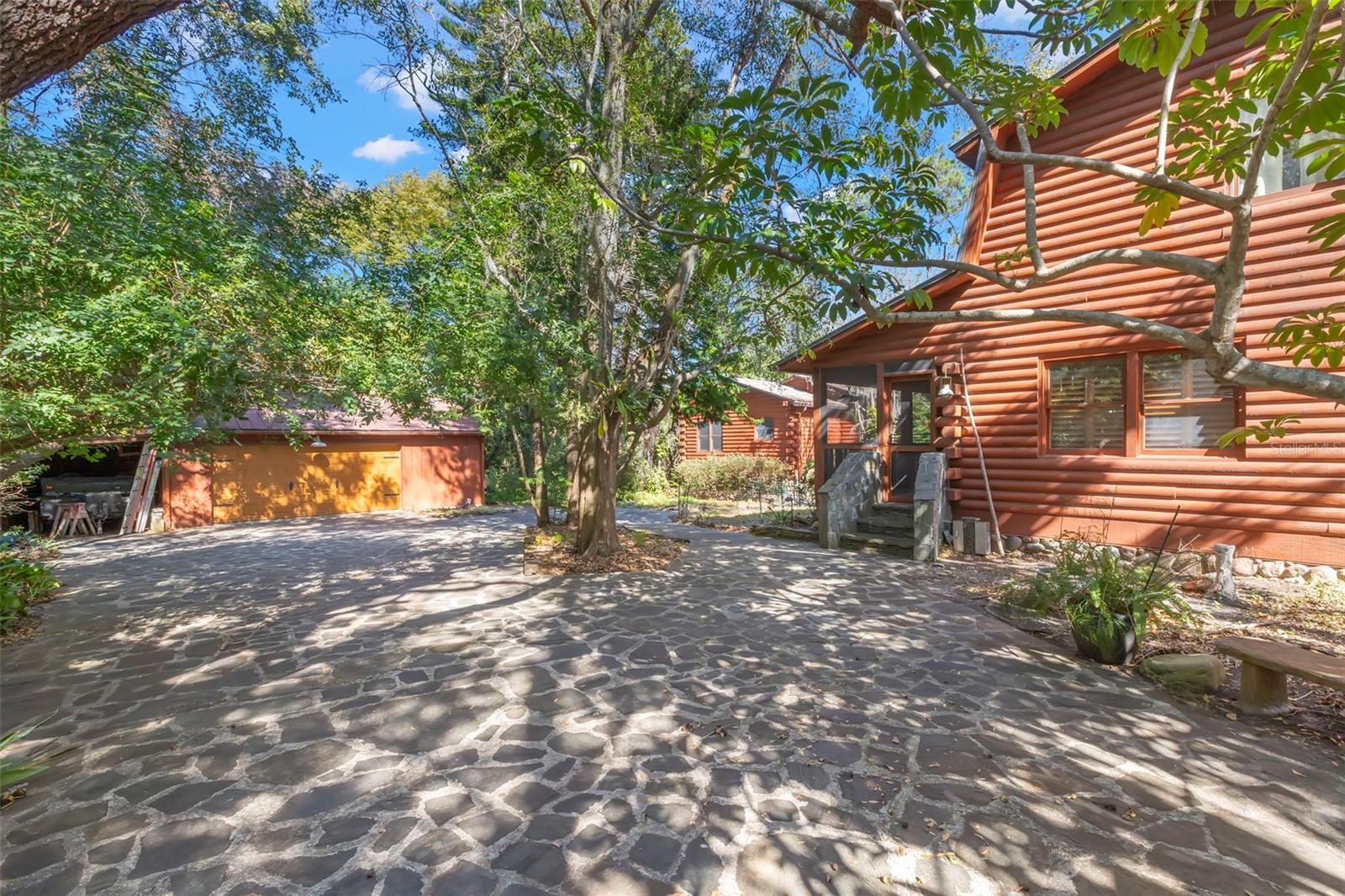 A thoughtfully arranged compound where the main residence, detached guest house, and 2.5-car garage and carport with electric are connected by a wide stone drive, creating a sense of privacy, flow, and cohesion. Mature trees and natural landscaping frame the structures, reinforcing the property’s rustic character while offering generous separation between living, hosting, and utility spaces.