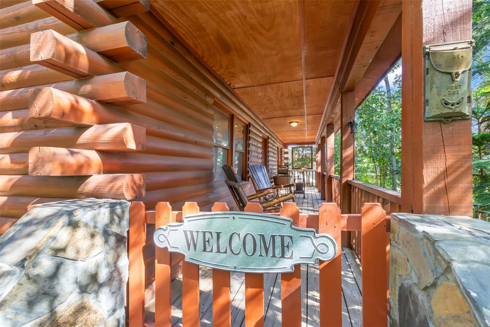 Covered front porch detail featuring stone pillars, wood railings, and a welcoming gate that reinforces the home’s rustic charm.