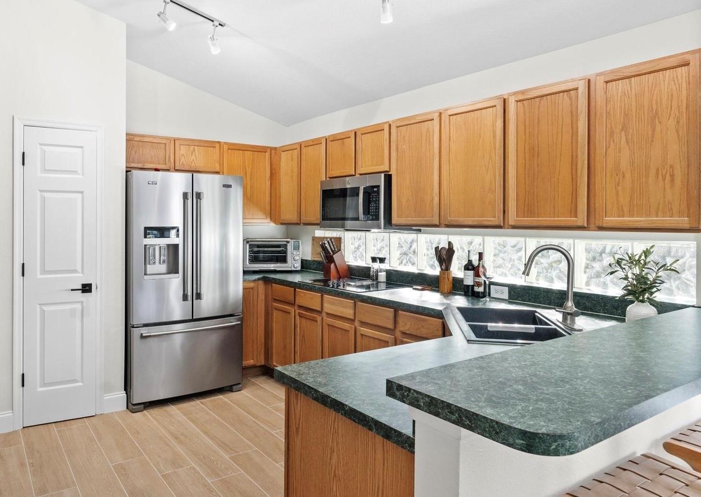 The kitchen is large and features a lot of cabinet space, a double oven, a cooktop, glass windows instead of backsplash, solid wood cabinets, and a counter for a couple of stools.  The pantry is larger on the inside.