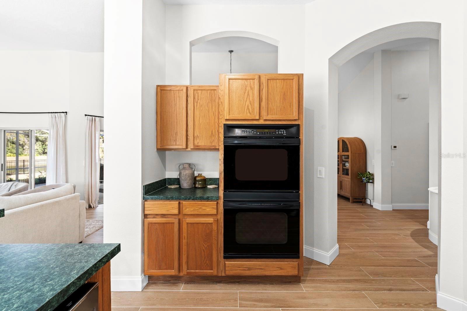 The kitchen is large and features a lot of cabinet space, a double oven, a cooktop, glass windows instead of backsplash, solid wood cabinets, and a counter for a couple of stools.  The same tile flooring is throughout the entire home!