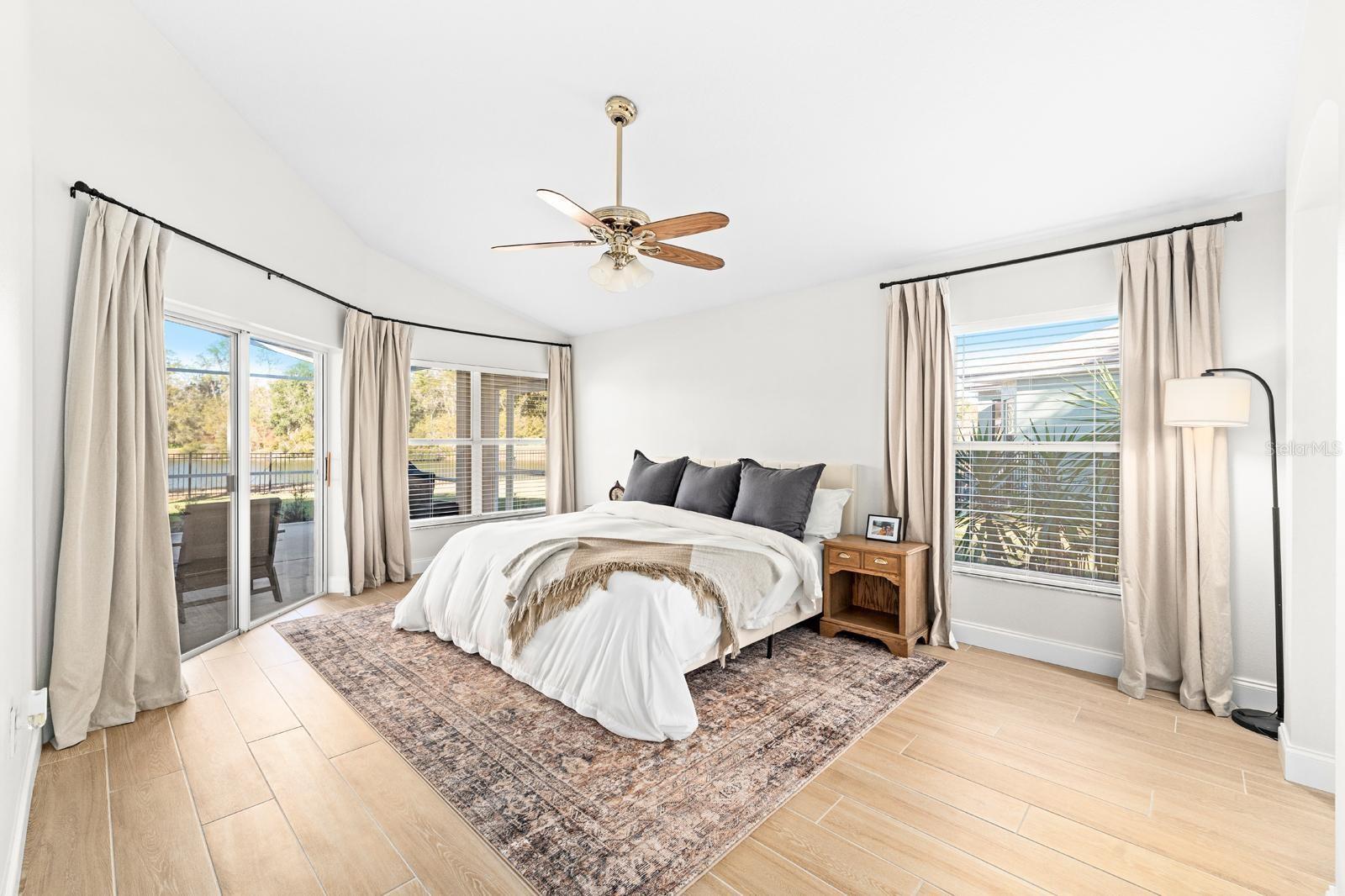 The very spacious primary bedroom features peaceful WATER VIEWS....the same plank tile flooring, vaulted ceilings, an oversized walk-in closet, and a slider to the screened-in patio.