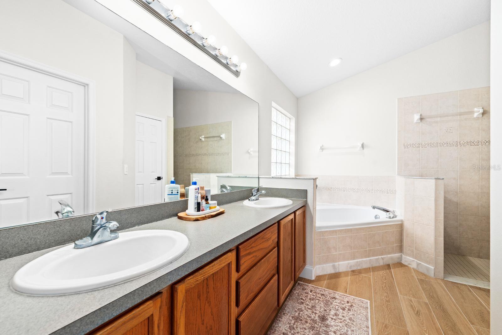 The large primary bathroom features dual sinks, lots of storage, a soaking tub, a spacious walk-in shower, a private toilet room, and a linen closet.