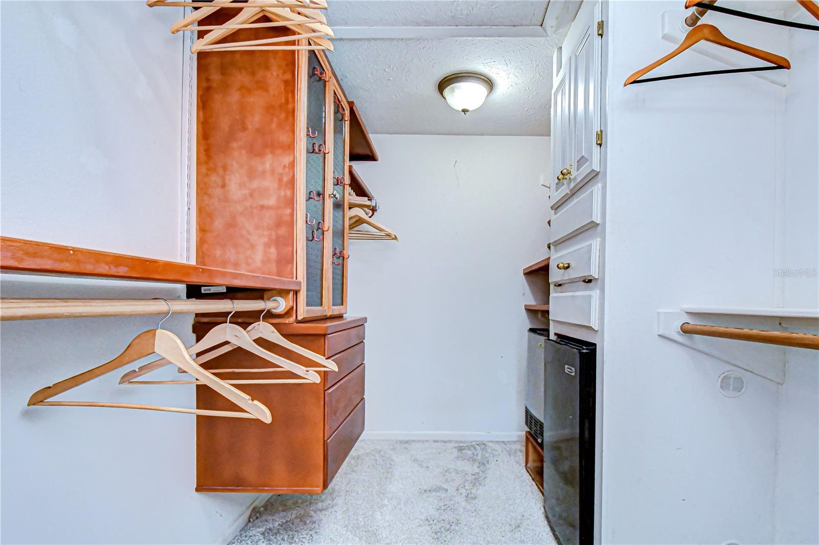Primary bedroom walk-in closet with ice machine and mini fridge.