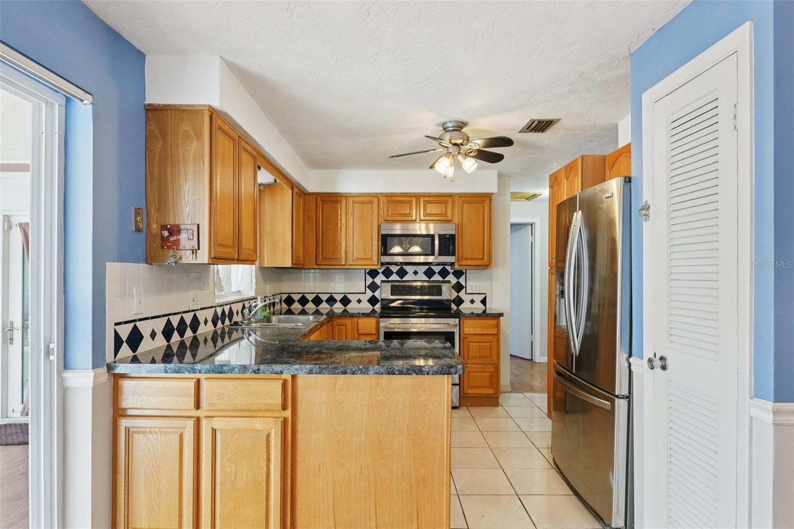 Kitchen with stainless steel appliances, granite countertops, pantry and window over sink