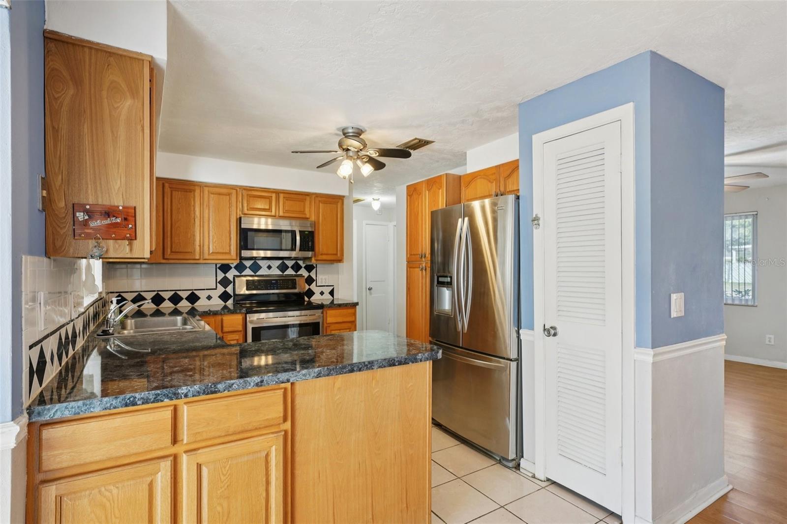 Kitchen with stainless steel appliances, granite countertops, pantry and window over sink