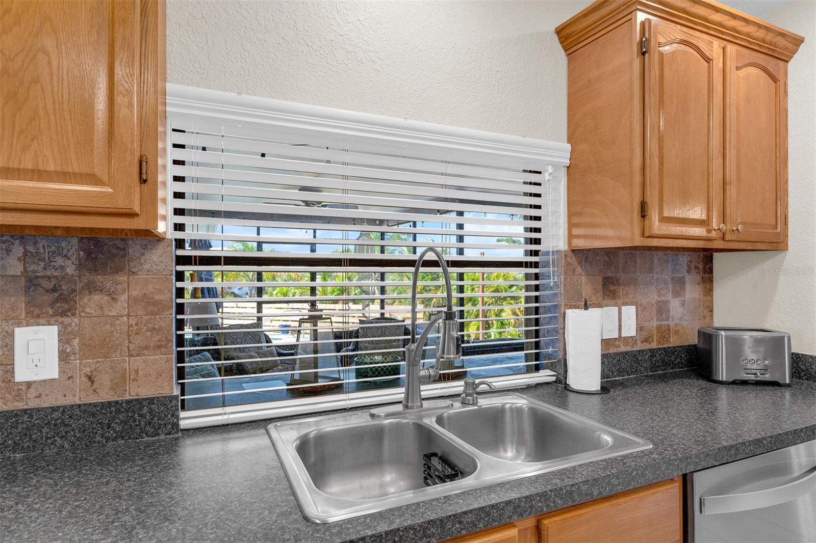 Stainless sink looking out to screened patio/lanai area.  Pass through for entertaining.