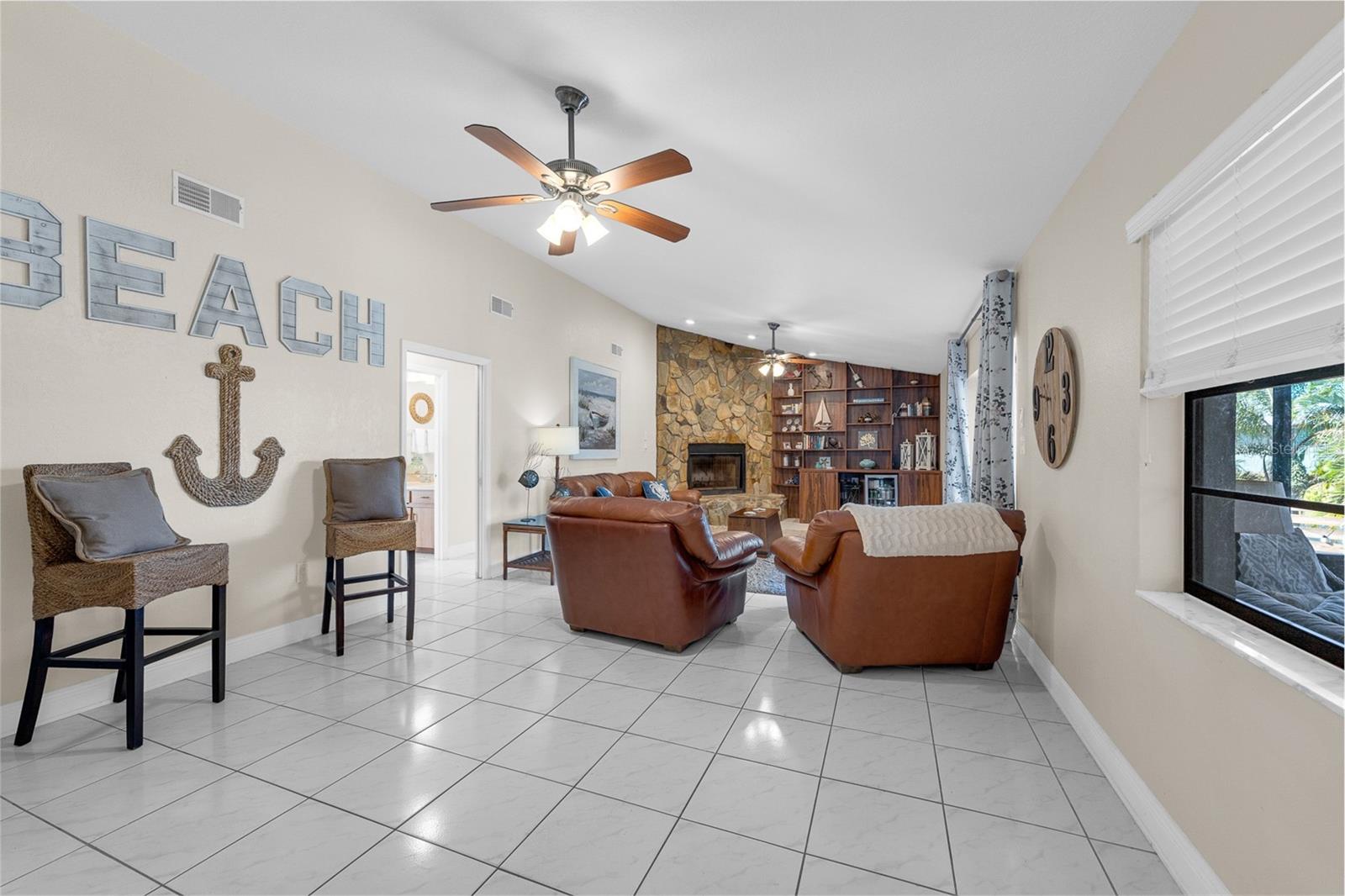 Open Family room with wood burning fireplace, and cathedral ceiling. Sliders lead onto large screened lanai and open pool deck.