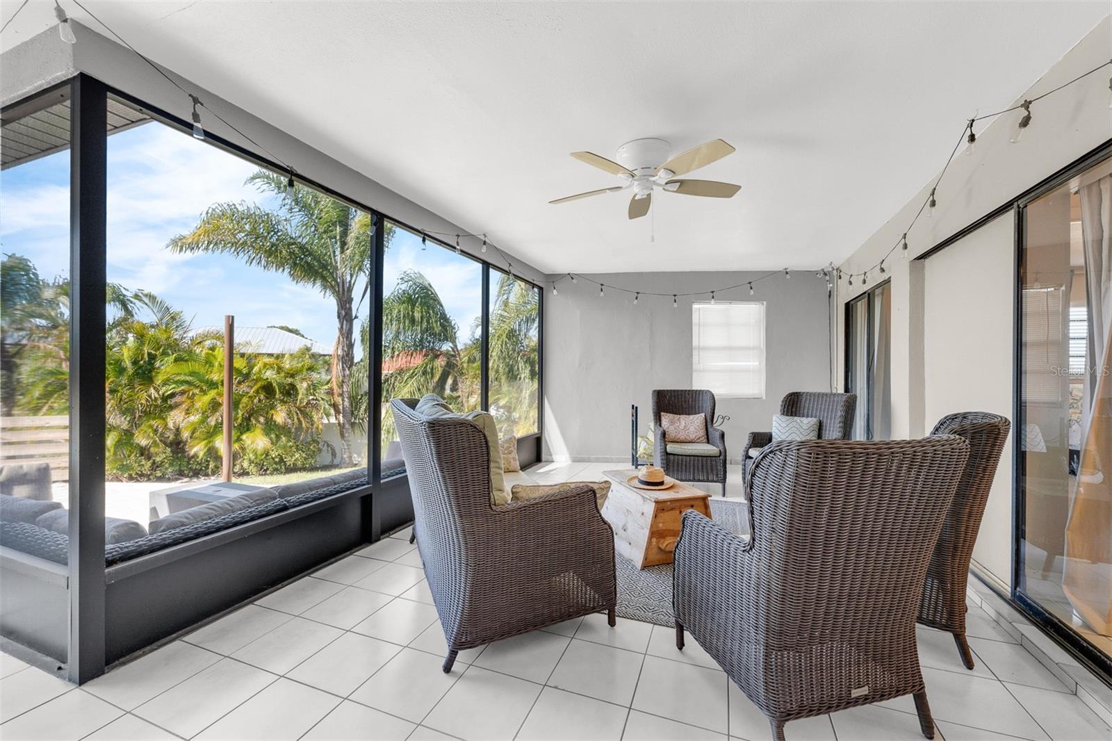 Sitting area on screened in lanai just outside the dining area and the primary or master bedroom, overlooking the pool deck.  Plenty of privacy with  mature landscaping.