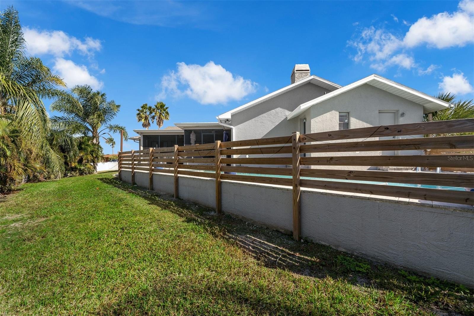 Back elevation of the pool deck with privacy fencing and mature landscaping