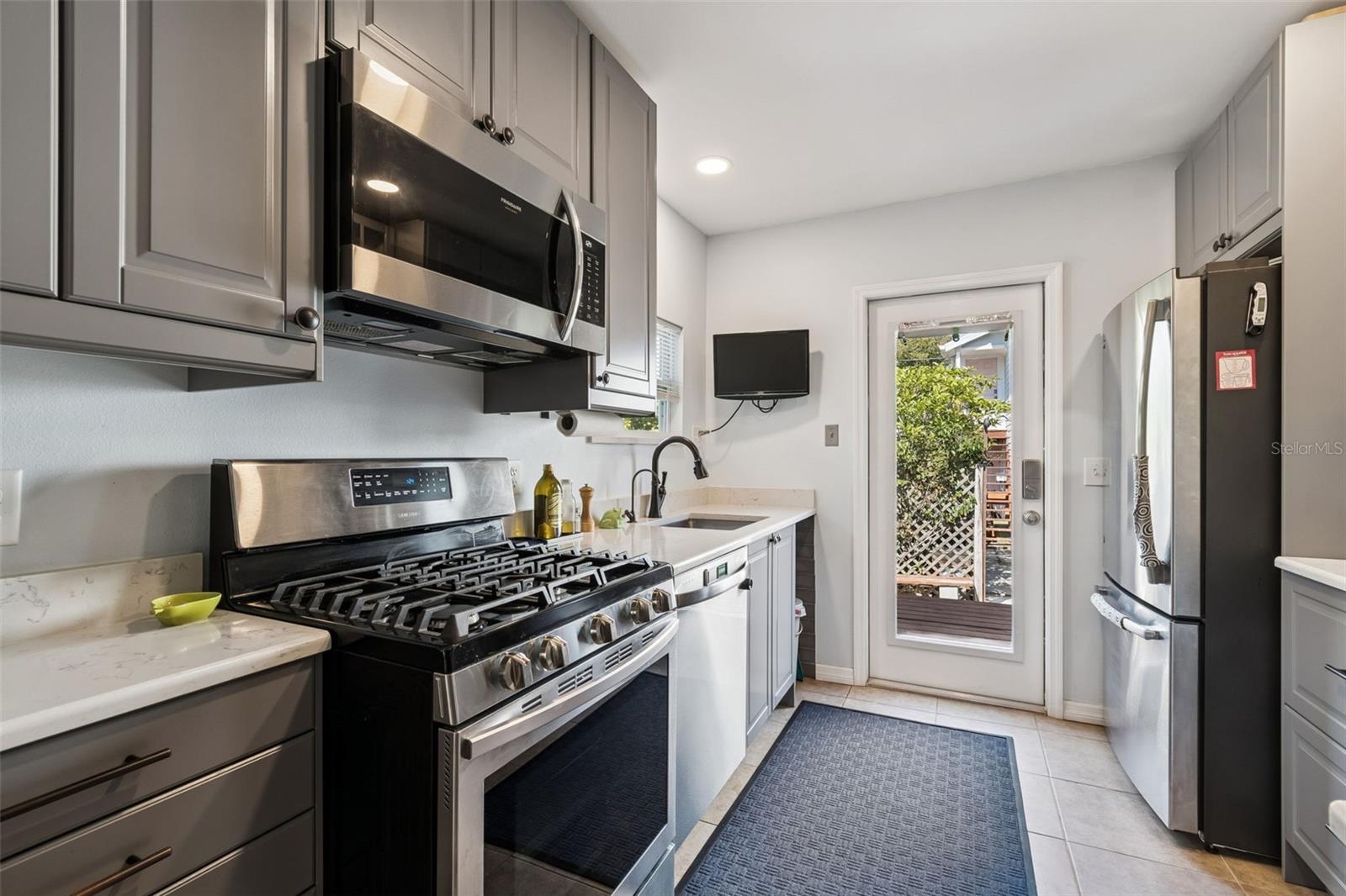 Stainless Steel appliances with door to back deck and yard