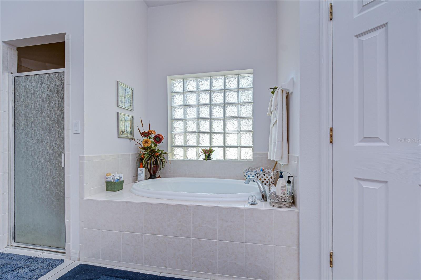 Relax in a spa-like bathroom with a soaking tub, tiled surround, and bright glass-block window!