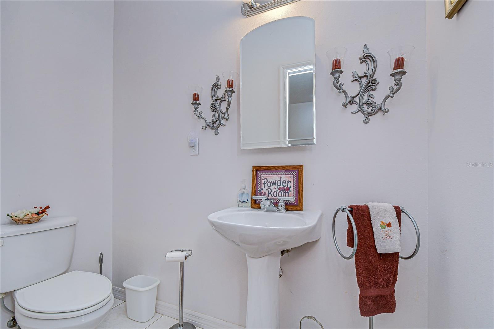 Bright powder bath featuring a pedestal sink, and arched mirror!