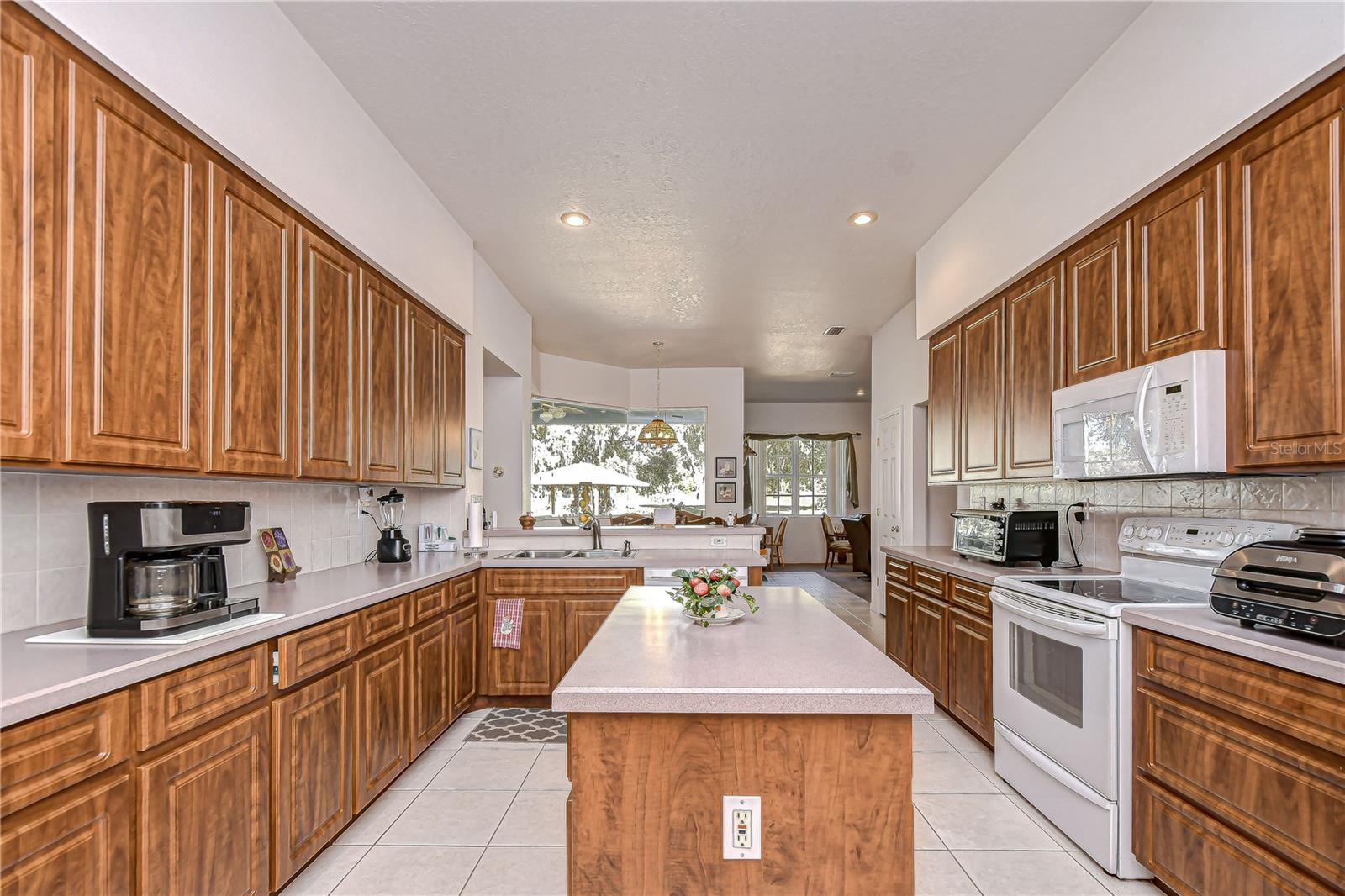 Bright, open kitchen featuring abundant wood cabinetry, expansive countertops, and a generous island under recessed lighting!