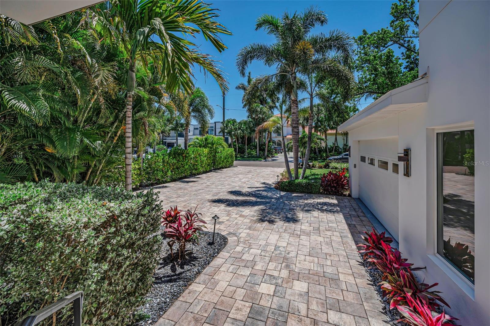Vinyl fence gate leads to front of the house on a meticulously kept paved path.