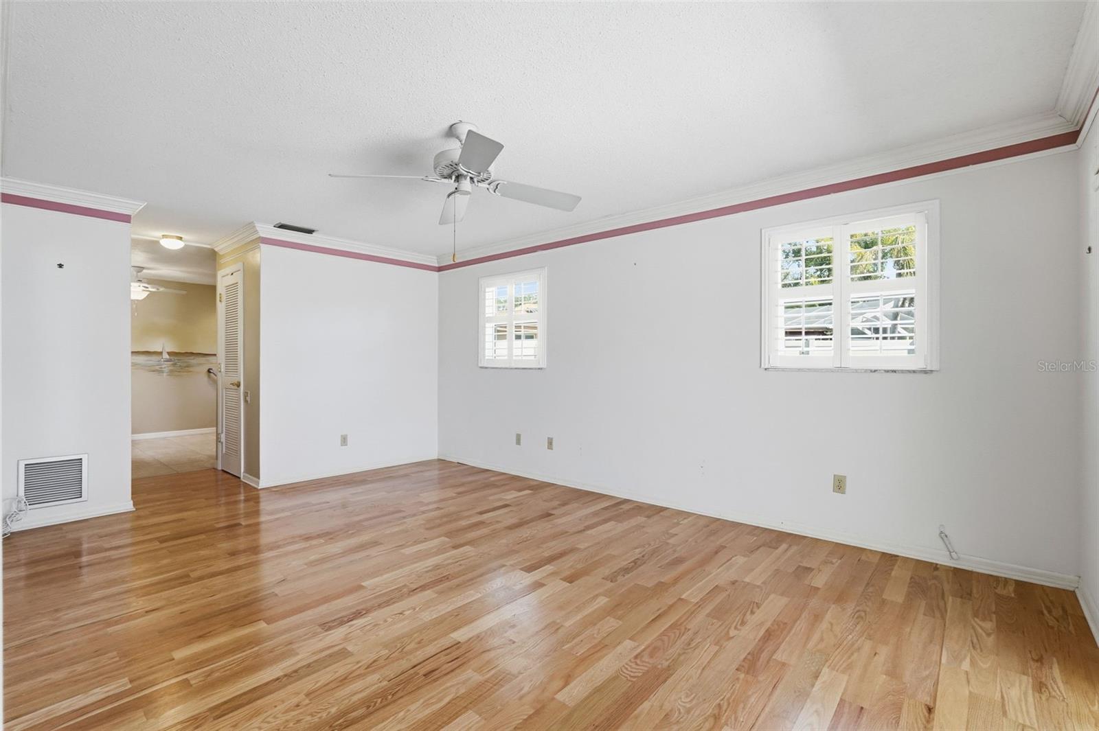 Primary Bedroom/Bath with wood floors, Plantation Shutters overlooking Lanai & Pool